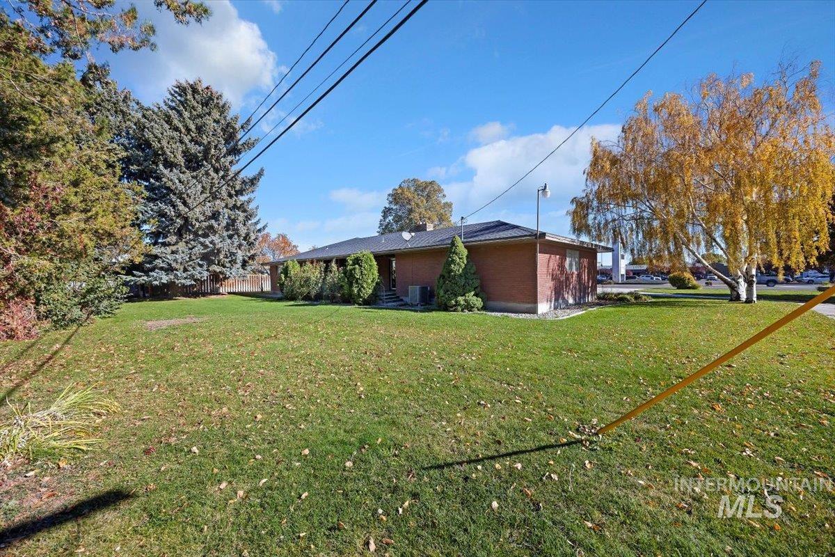 View of side of property featuring a lawn, brick siding, and a chimney