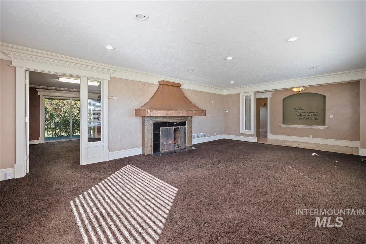 Unfurnished living room with ornamental molding, a fireplace, dark carpet, and recessed lighting