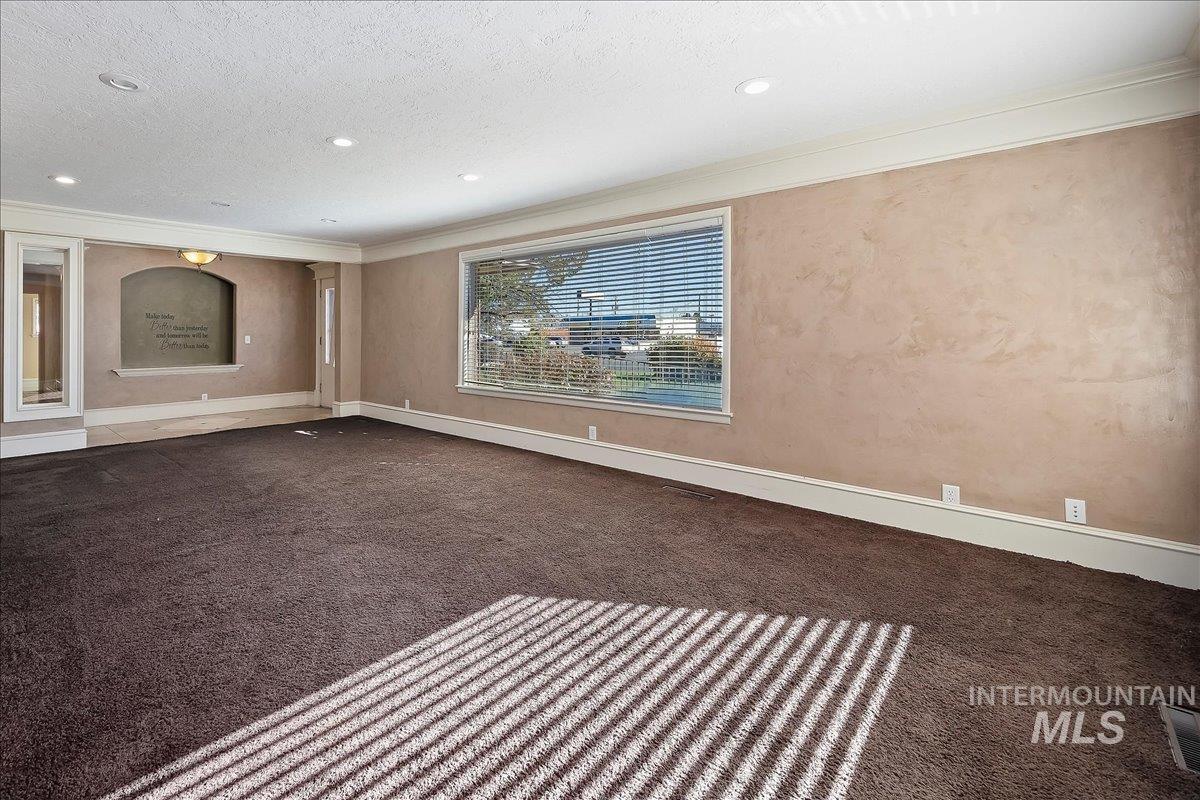 Carpeted empty room featuring ornamental molding, recessed lighting, and a textured ceiling