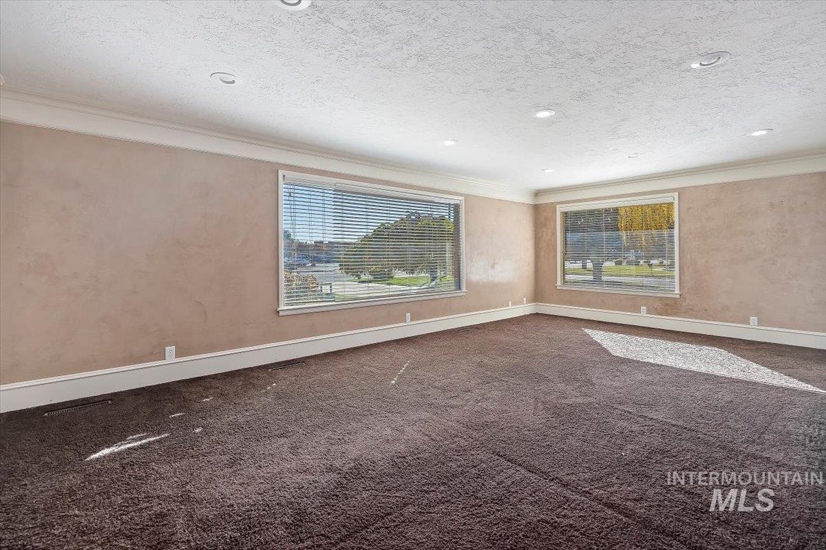 Spare room featuring crown molding, dark colored carpet, a textured ceiling, and recessed lighting