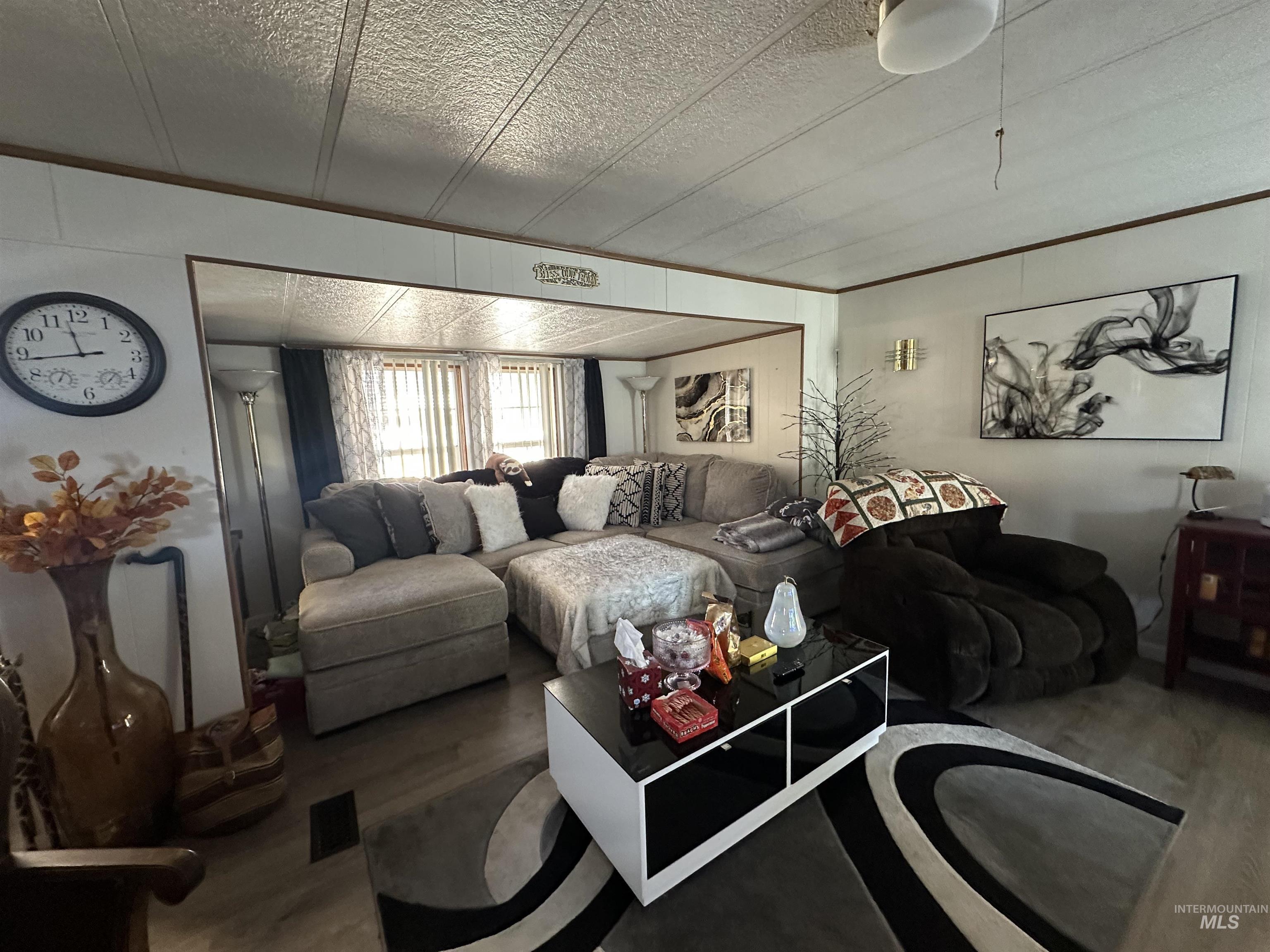 Living room featuring wood finished floors, ornamental molding, and a textured ceiling