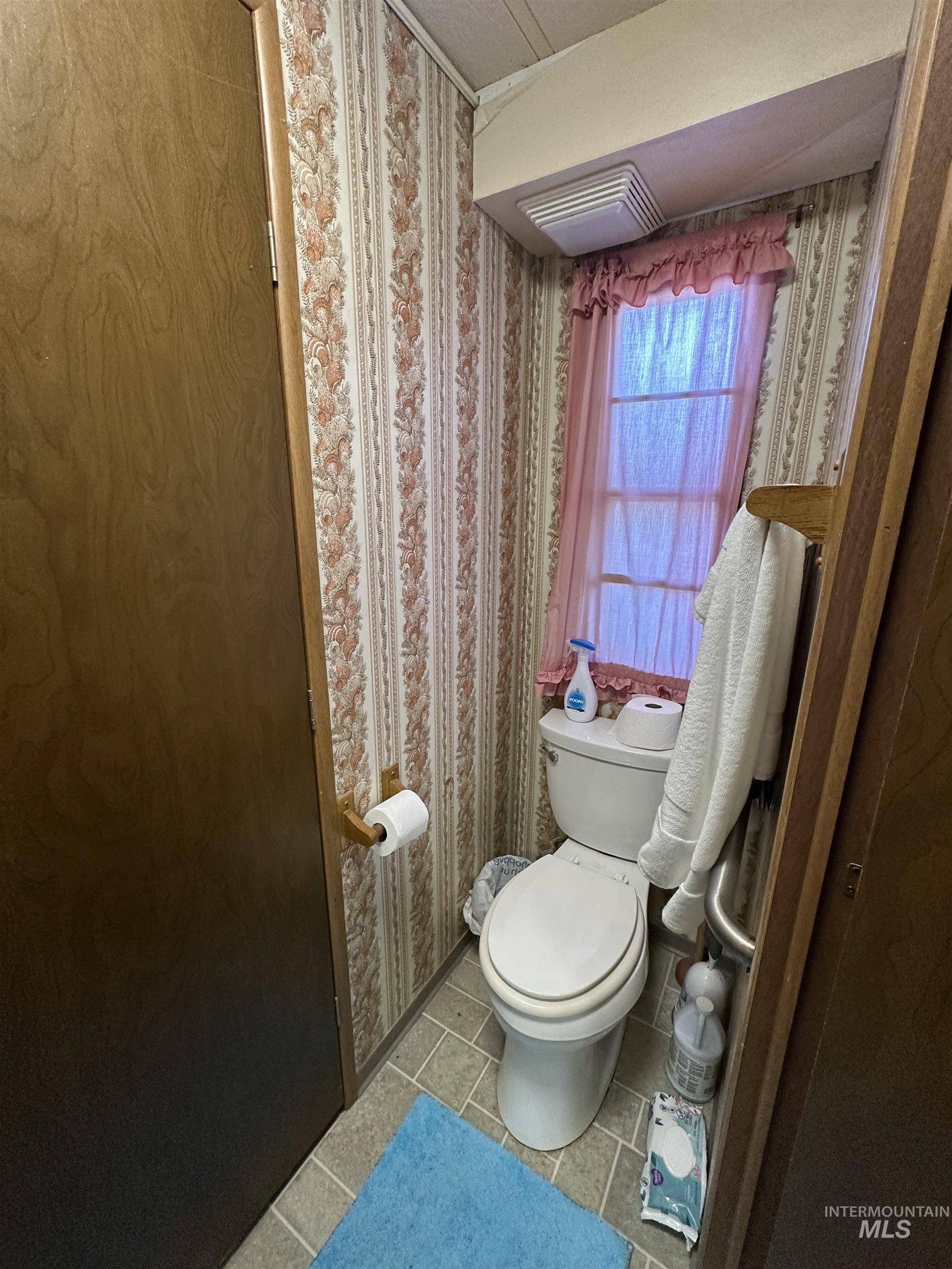 Bathroom with wallpapered walls and tile patterned floors