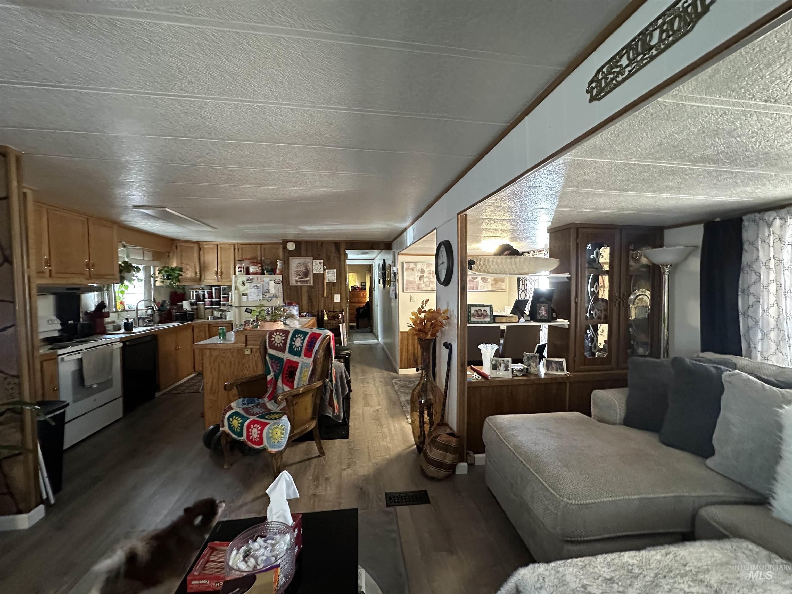 Living room featuring a textured ceiling, dark wood finished floors, and wood walls