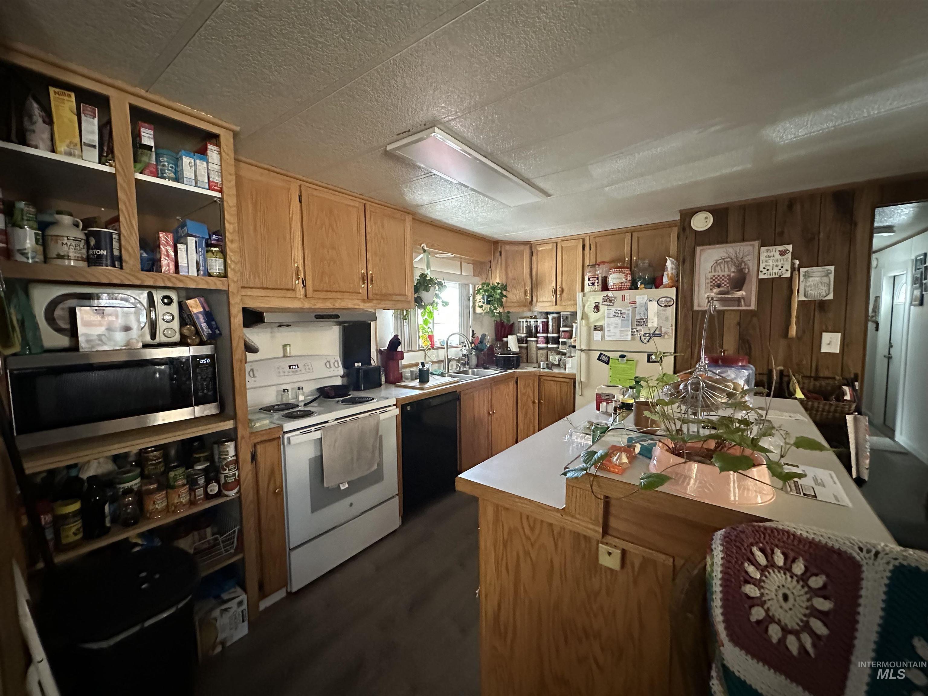 Kitchen with white appliances, light countertops, brown cabinetry, open shelves, and a kitchen island
