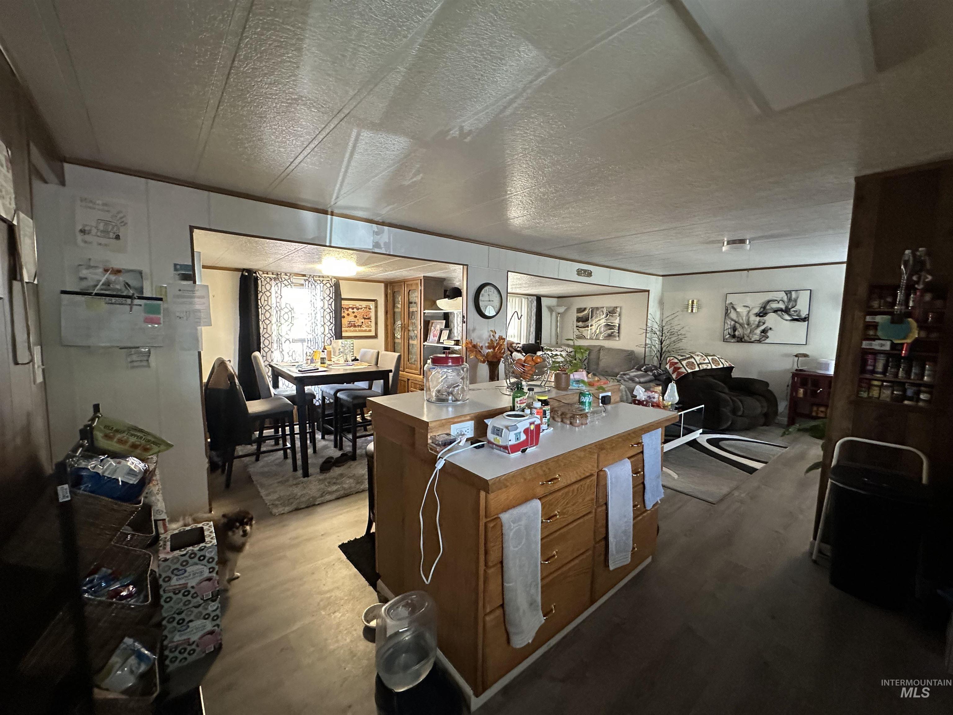 Kitchen with wood finished floors, a textured ceiling, light countertops, and brown cabinets