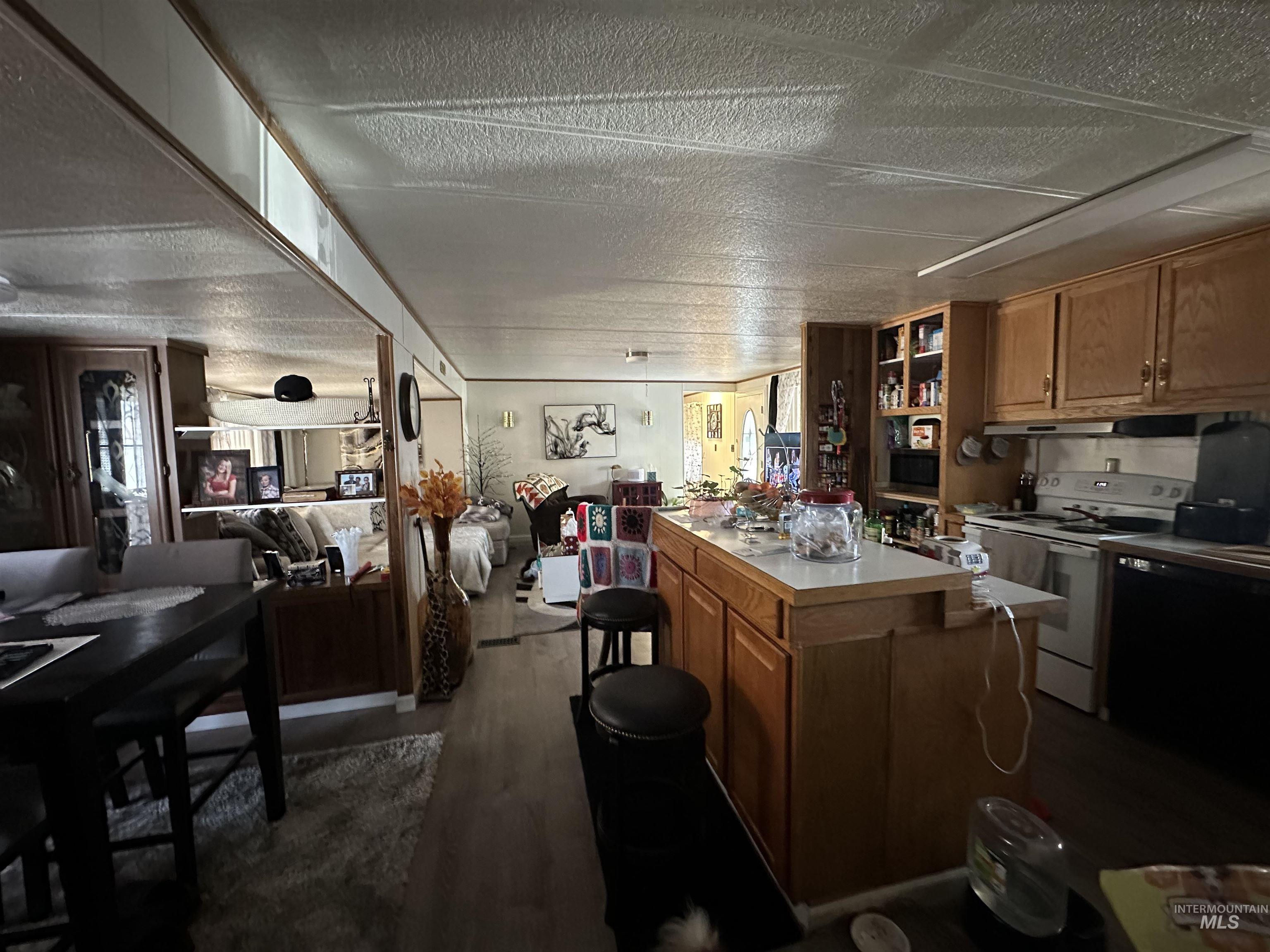 Kitchen featuring white electric stove, light countertops, dark wood-style floors, a textured ceiling, and open floor plan