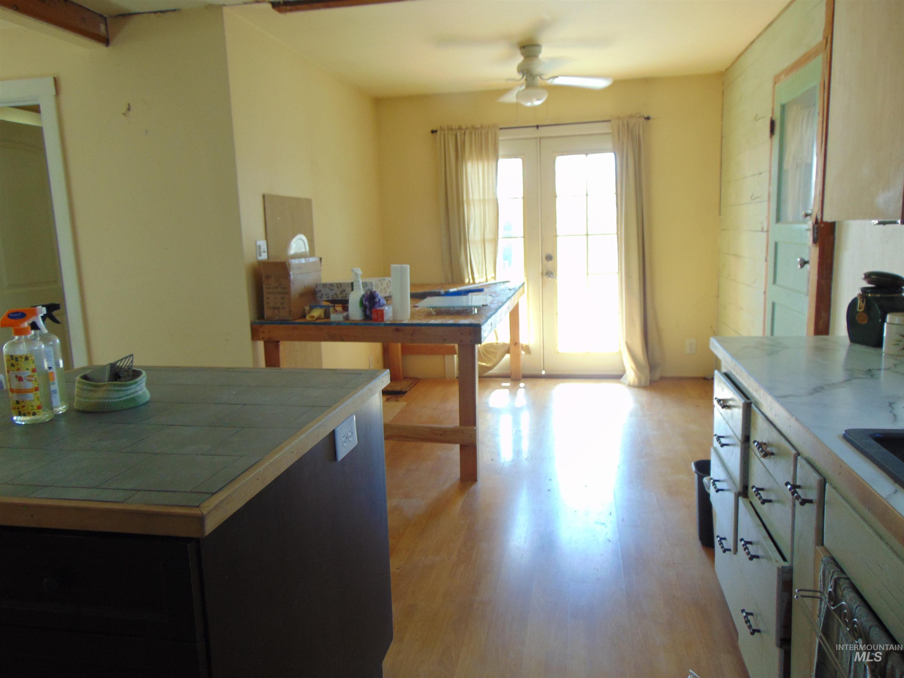 Kitchen with tile countertops, light wood-type flooring, a ceiling fan, french doors, and wall oven