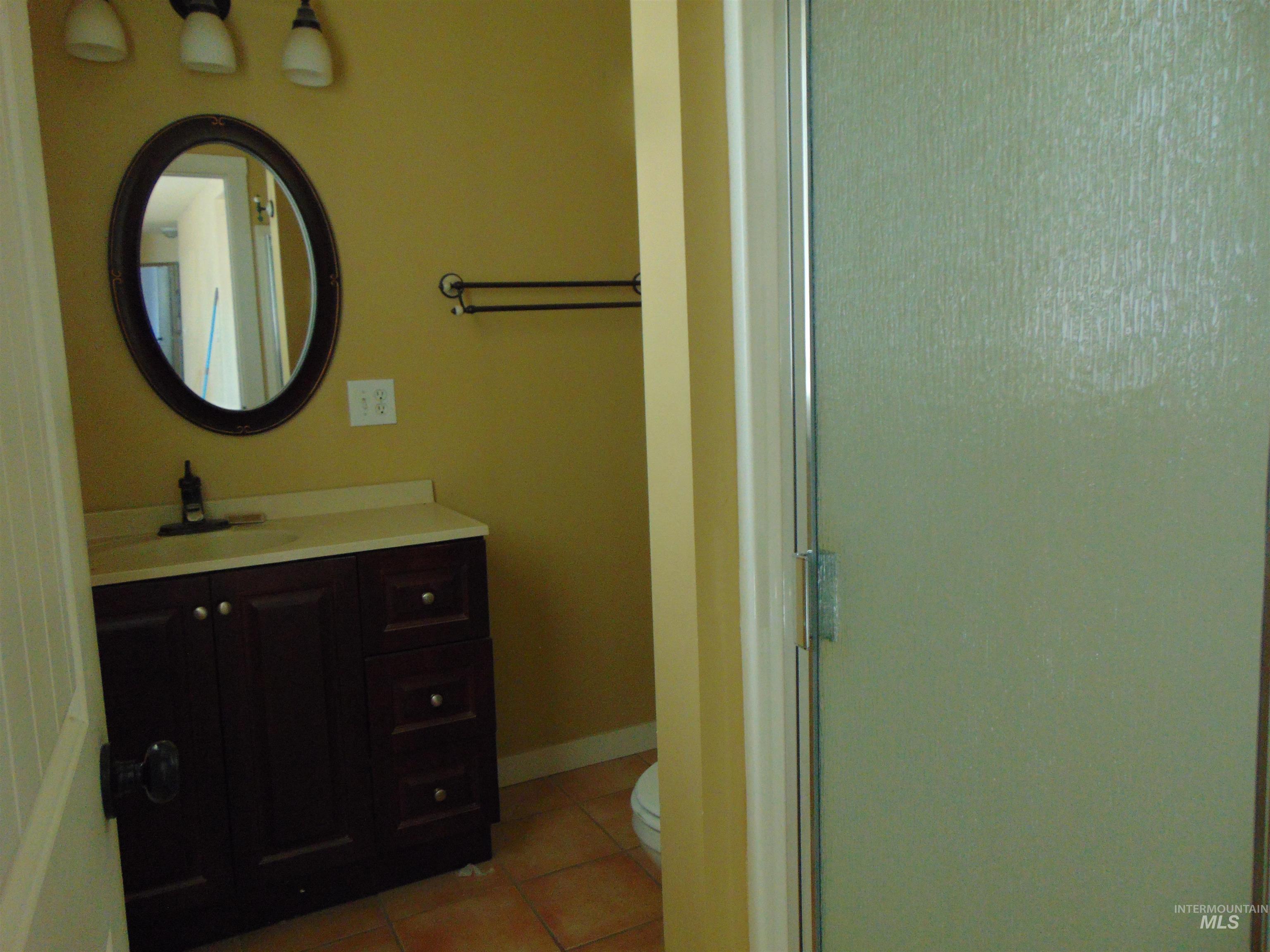 Full bathroom with light tile patterned floors, vanity, and a shower stall
