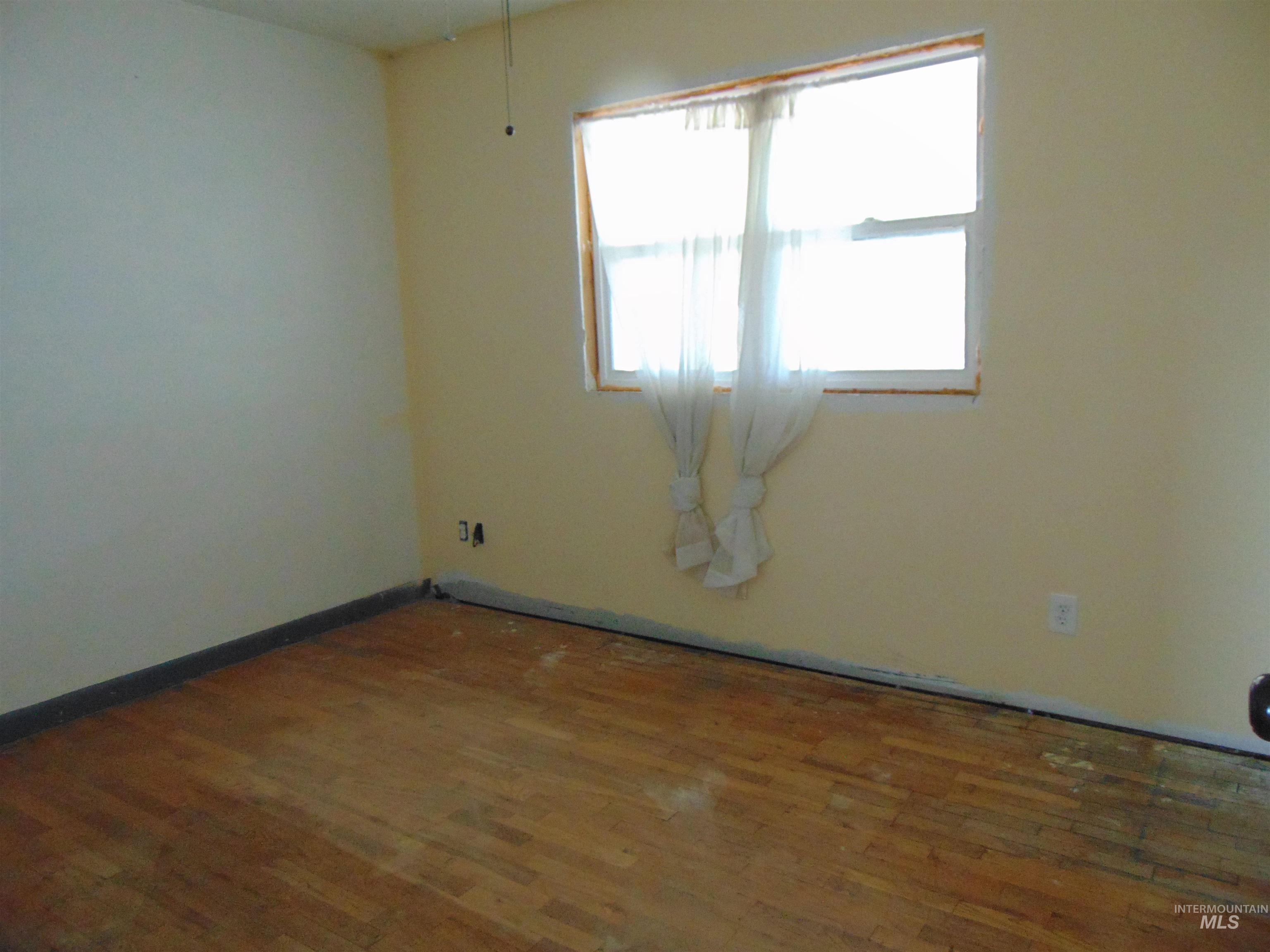 Empty room featuring dark wood-style flooring and baseboards