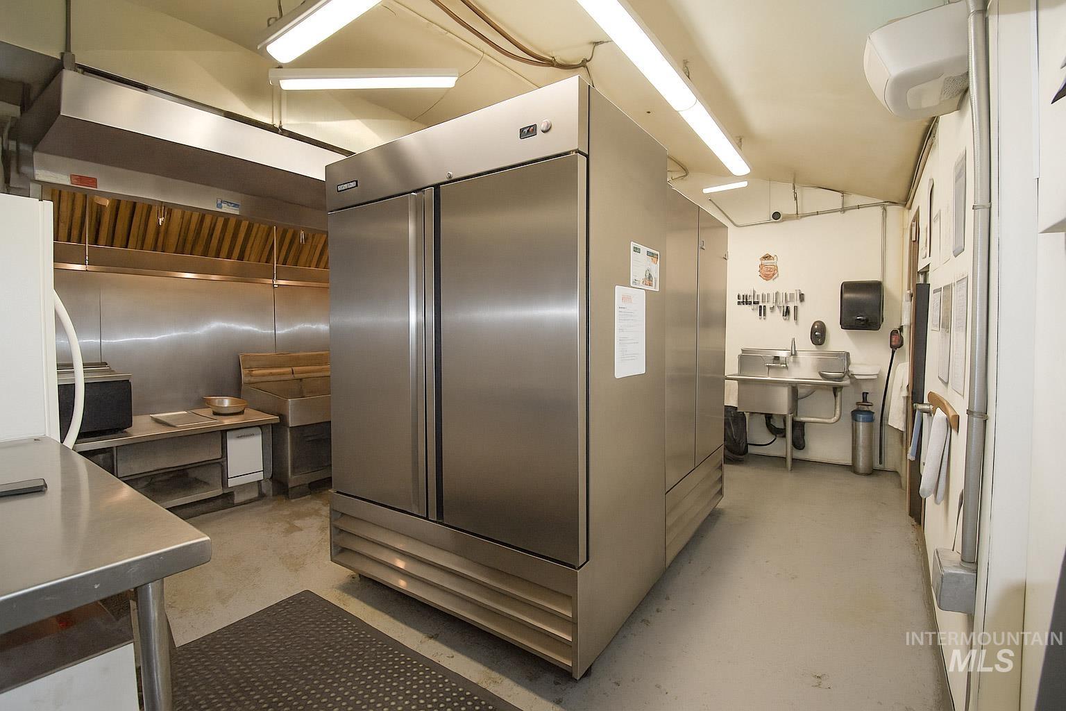 Kitchen featuring range hood, high end fridge, and stainless steel counters