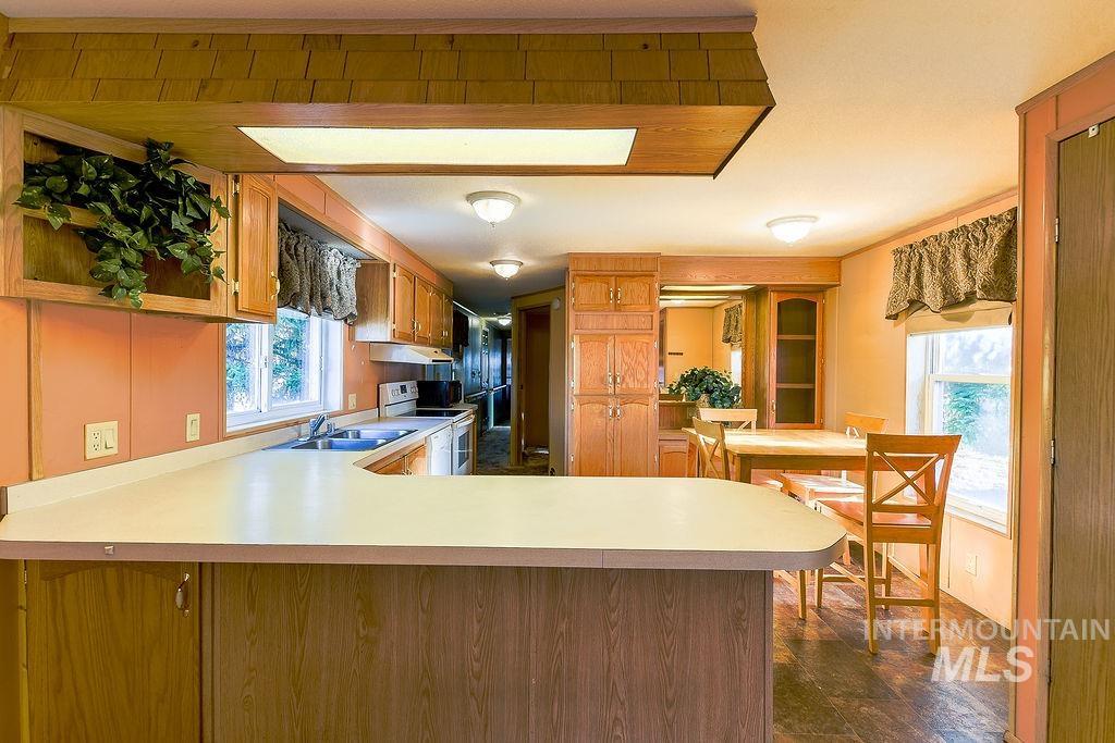 Kitchen featuring light countertops, plenty of natural light, brown cabinets, and crown molding