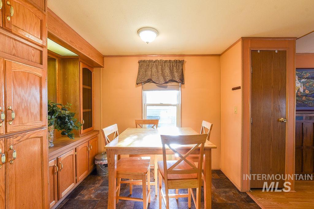 Dining space featuring dark stone finish floors and crown molding