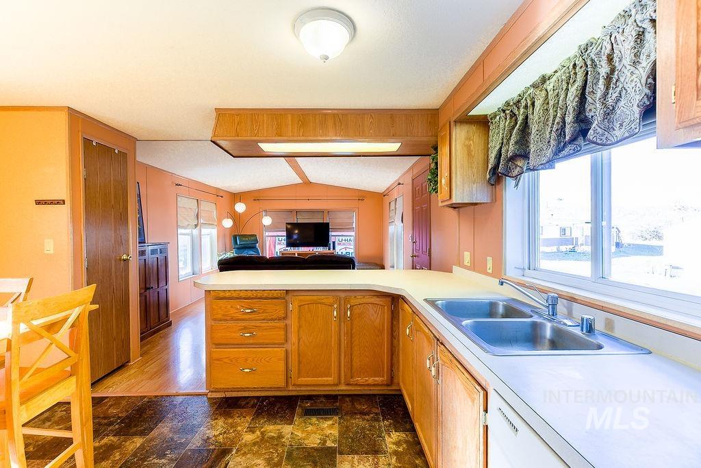 Kitchen with open floor plan, a peninsula, light countertops, lofted ceiling, and brown cabinets