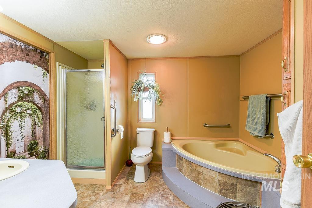 Bathroom with a stall shower, a textured ceiling, and a bath