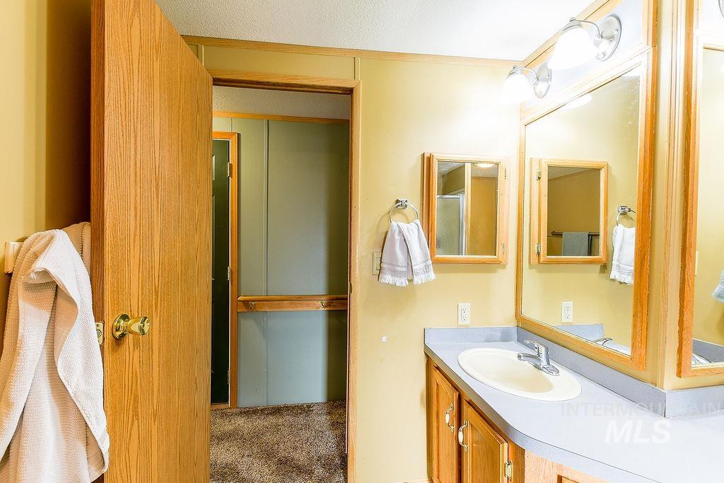 Bathroom with vanity, carpet floors, and a textured ceiling