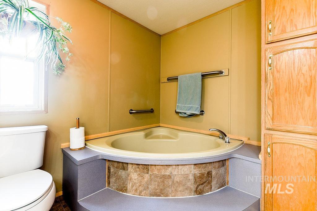 Full bath featuring a garden tub and toilet