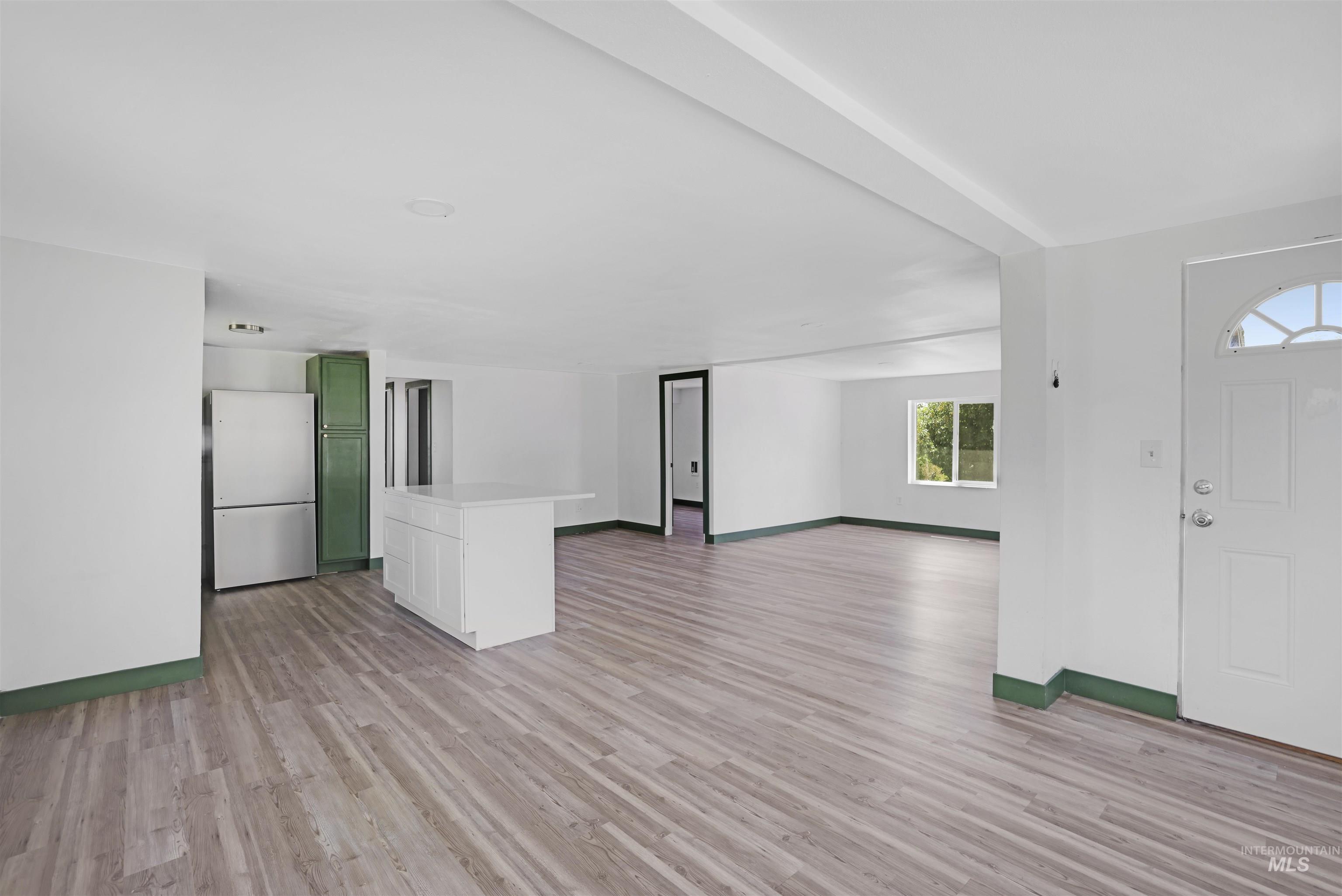 Unfurnished living room with light wood-style flooring and baseboards