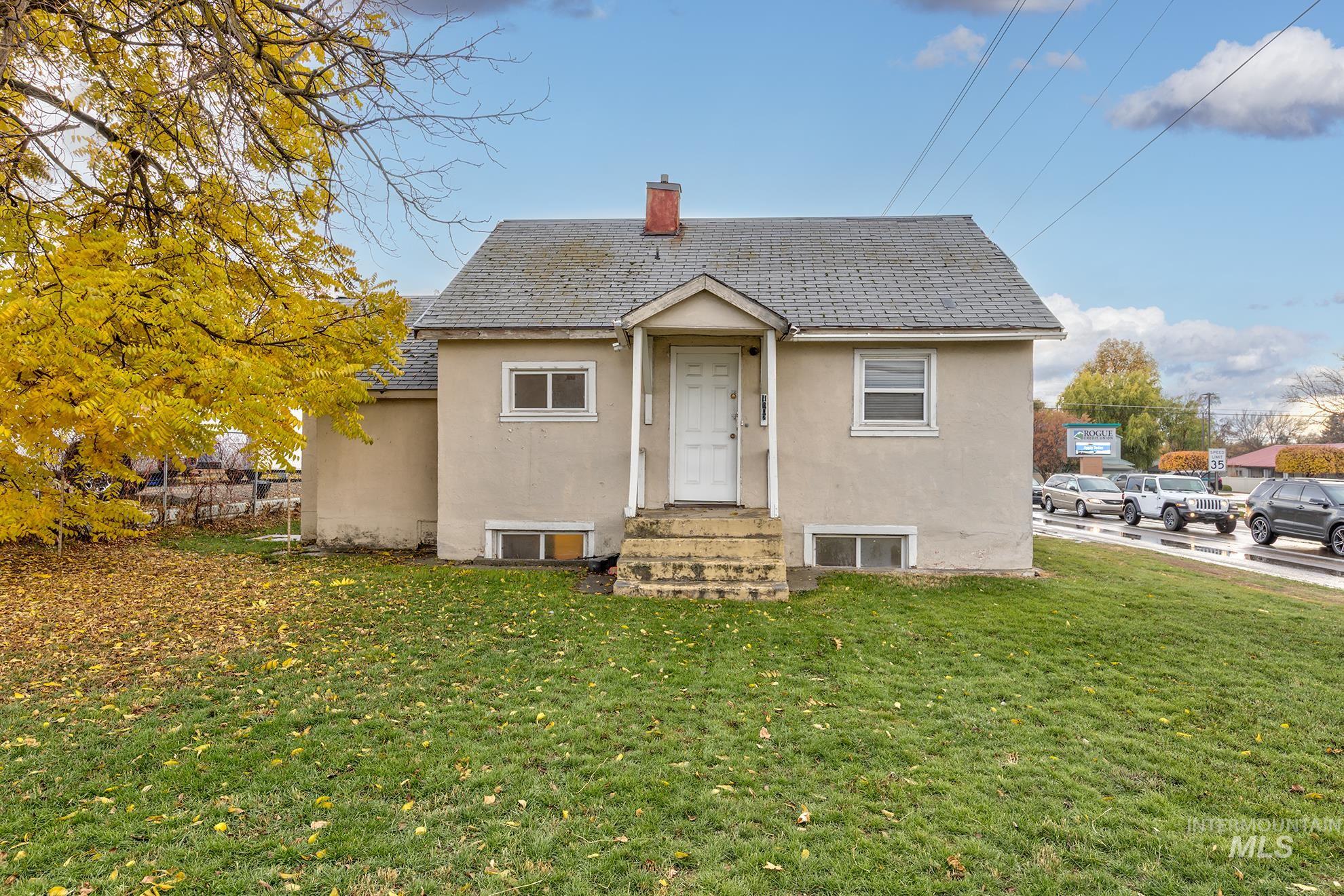 View of front of property with stucco siding, a front yard, a chimney, and entry steps