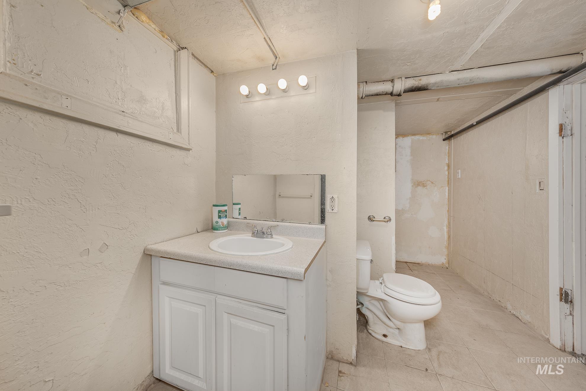 Full bathroom with a textured wall, vanity, light tile patterned floors, and a shower