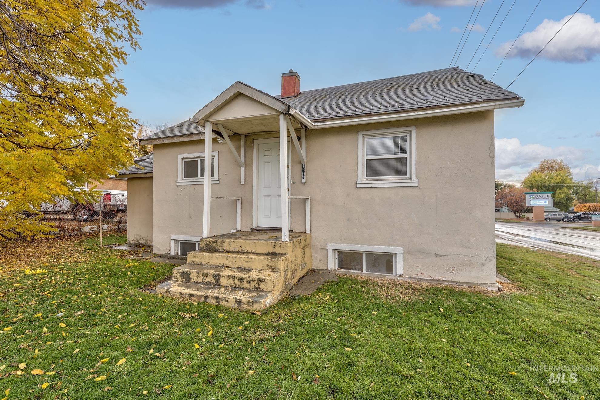 View of front of home featuring stucco siding, a front lawn, and a chimney