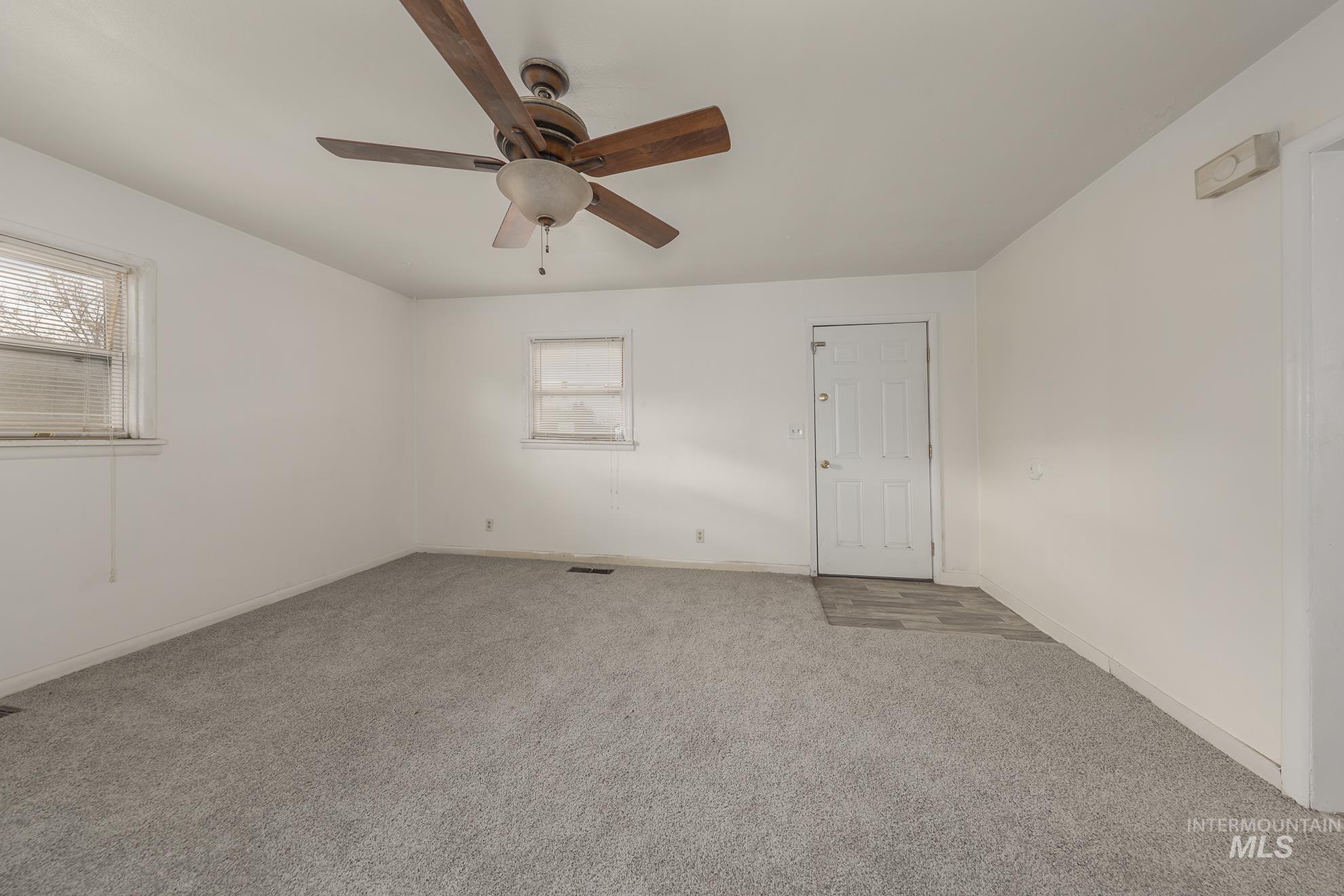 Carpeted spare room featuring baseboards and ceiling fan