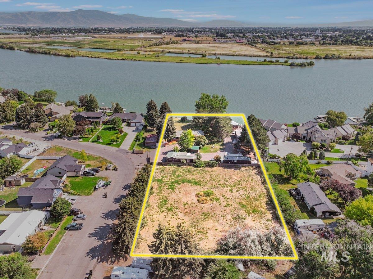 Aerial perspective of suburban area featuring a large body of water and property boundaries highlighted