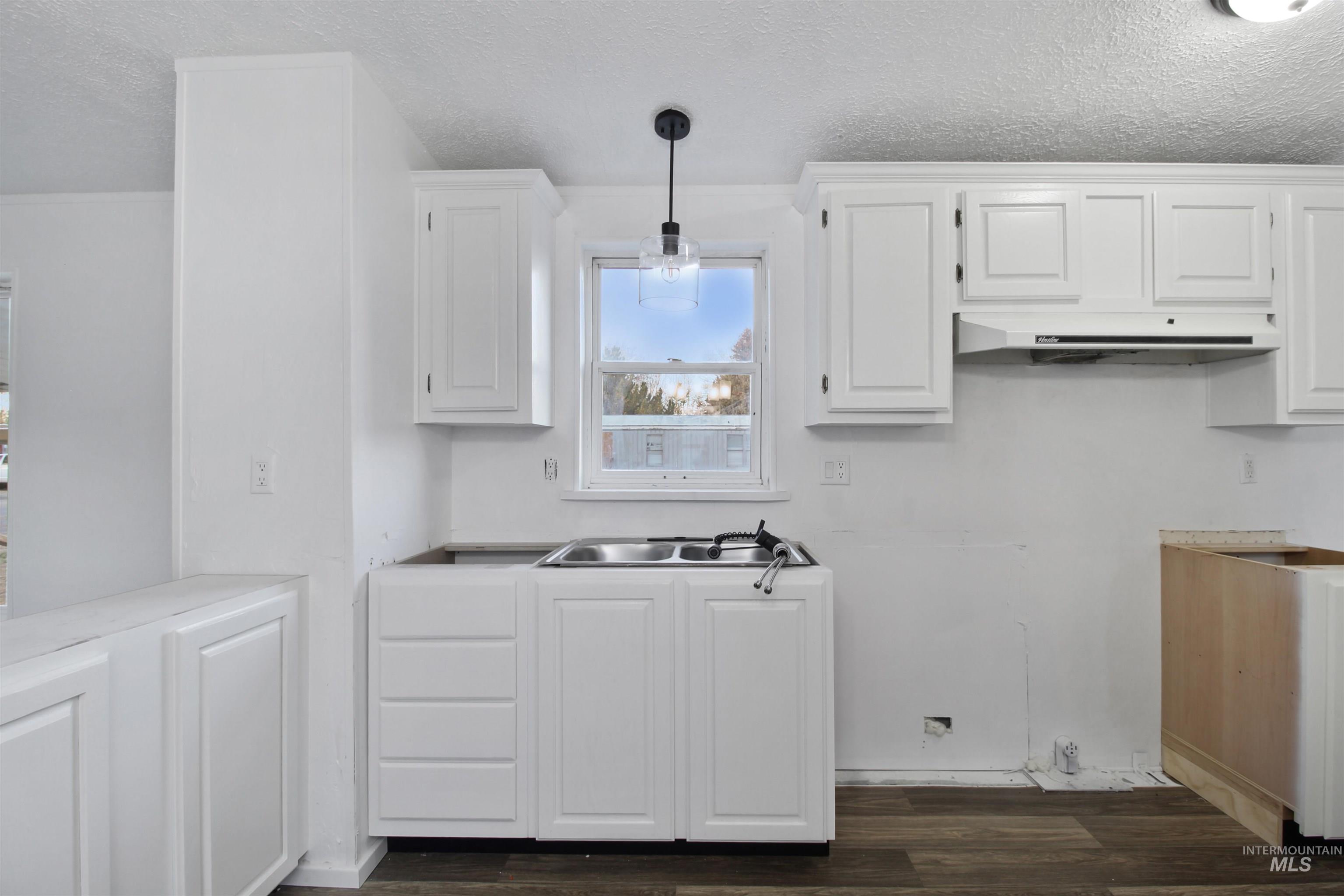 Kitchen with white cabinets, a textured ceiling, dark wood-style floors, pendant lighting, and light countertops