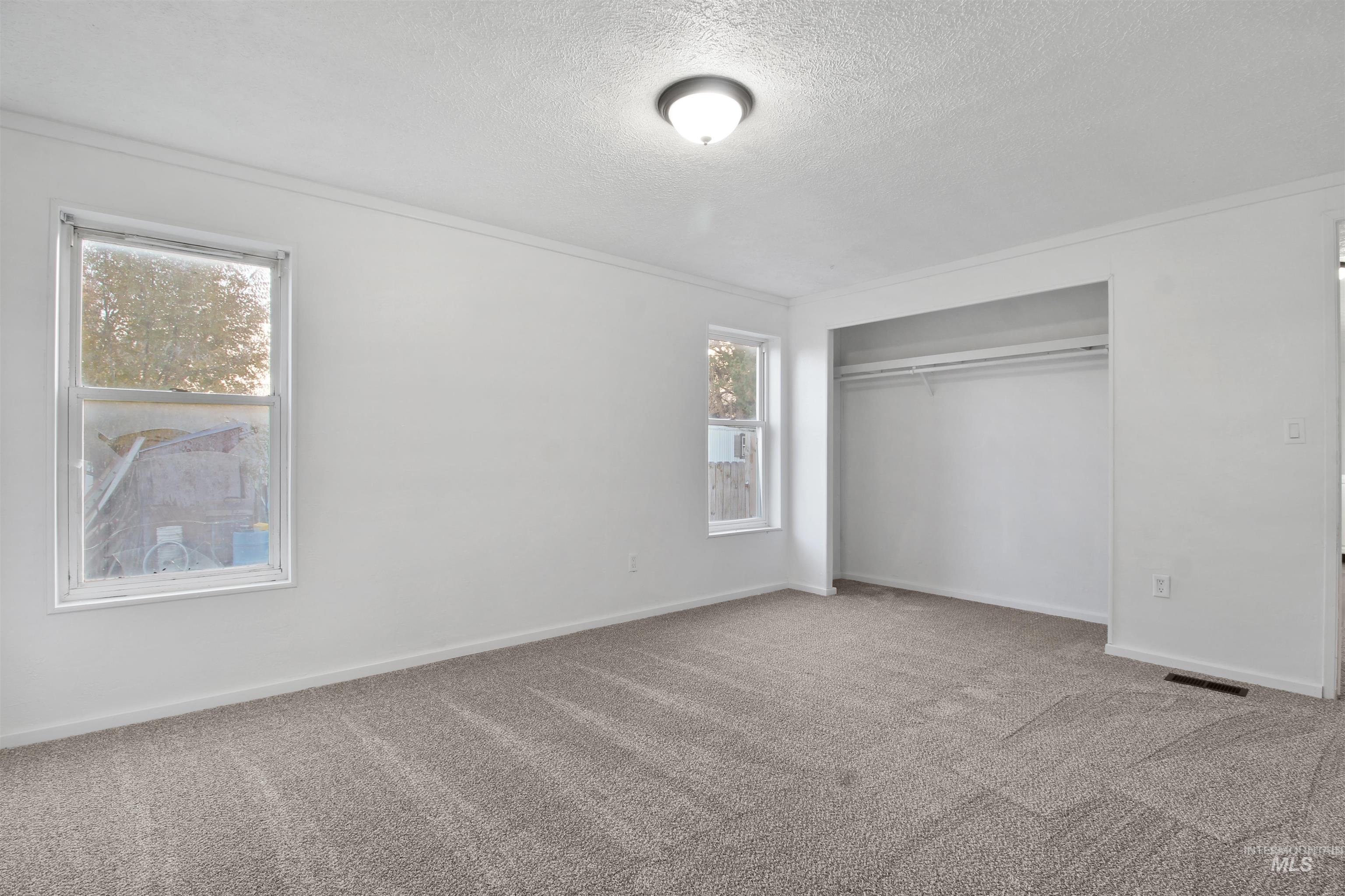Unfurnished bedroom with carpet floors, a closet, a textured ceiling, and ornamental molding