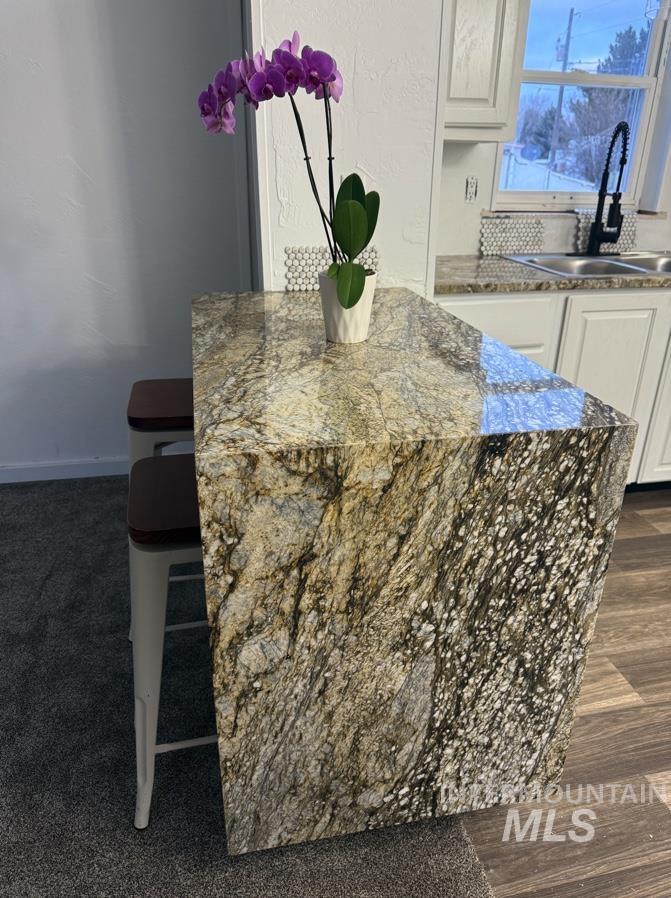 Kitchen view of dark stone countertops, white cabinetry, and a breakfast bar