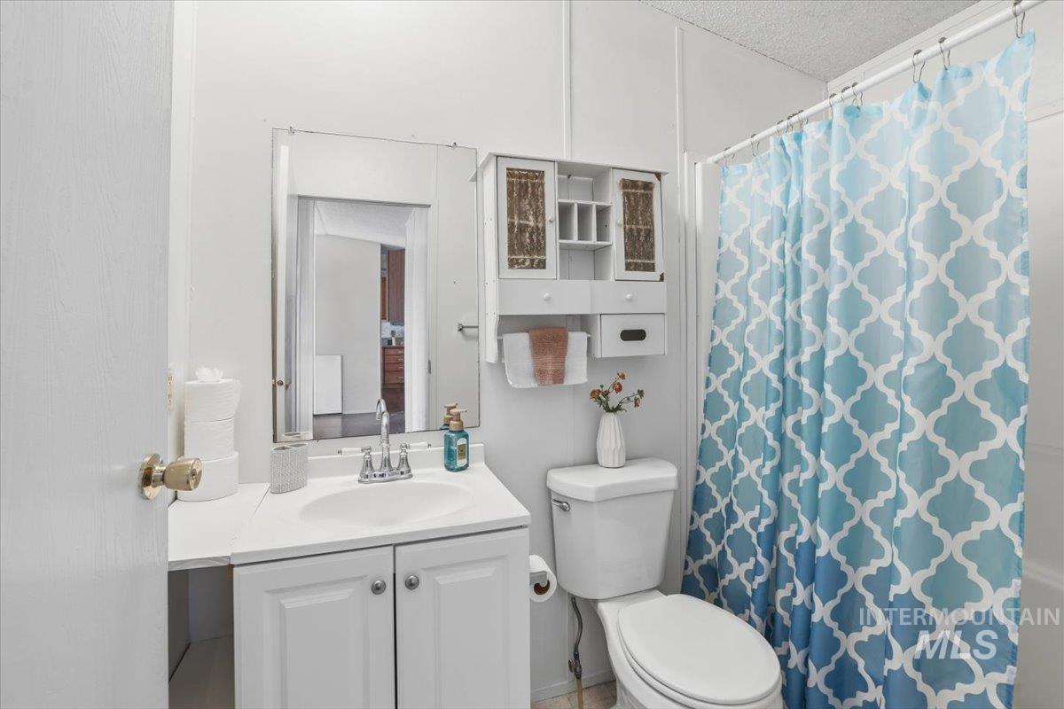 Bathroom featuring a shower with shower curtain, vanity, and a textured ceiling