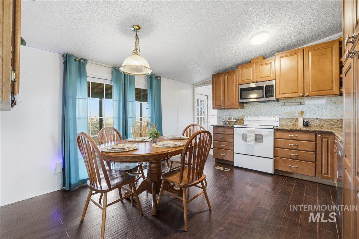 Kitchen featuring stainless steel appliances, a textured ceiling, healthy amount of natural light, tasteful backsplash, and pendant lighting