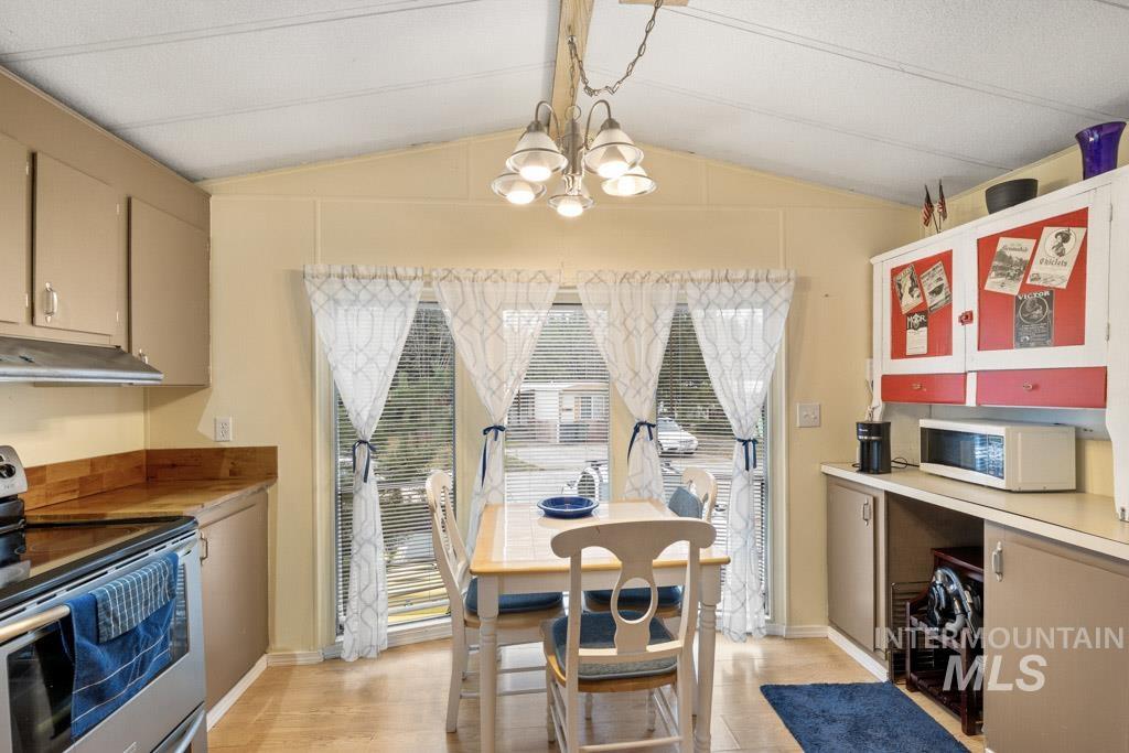 Dining area featuring vaulted ceiling, light wood-style floors, and a chandelier