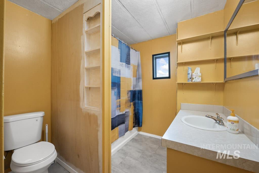 Bathroom featuring a shower with shower curtain, vanity, and a textured ceiling