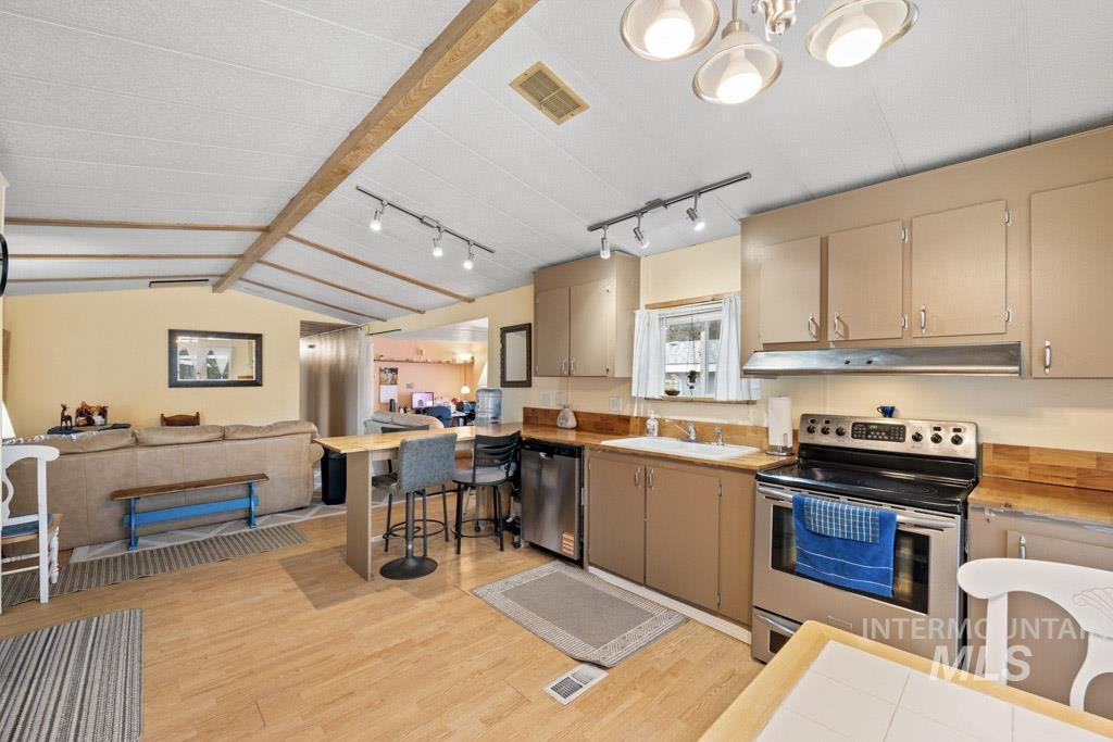 Kitchen with open floor plan, appliances with stainless steel finishes, light wood-type flooring, a kitchen bar, and a peninsula