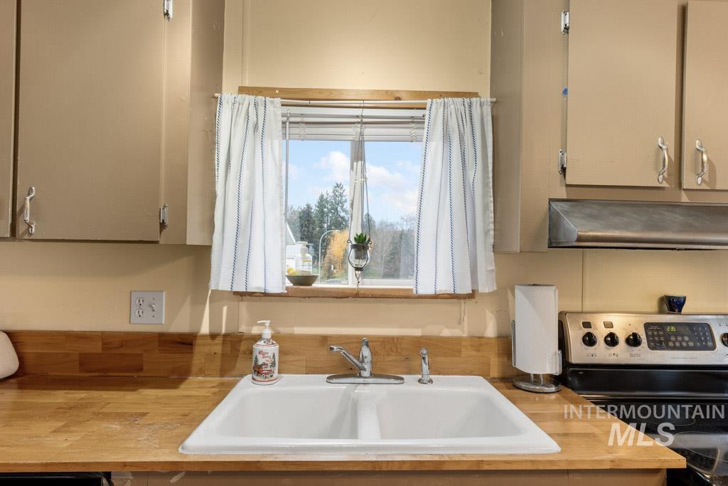 Kitchen with butcher block counters, stainless steel electric range oven, and exhaust hood