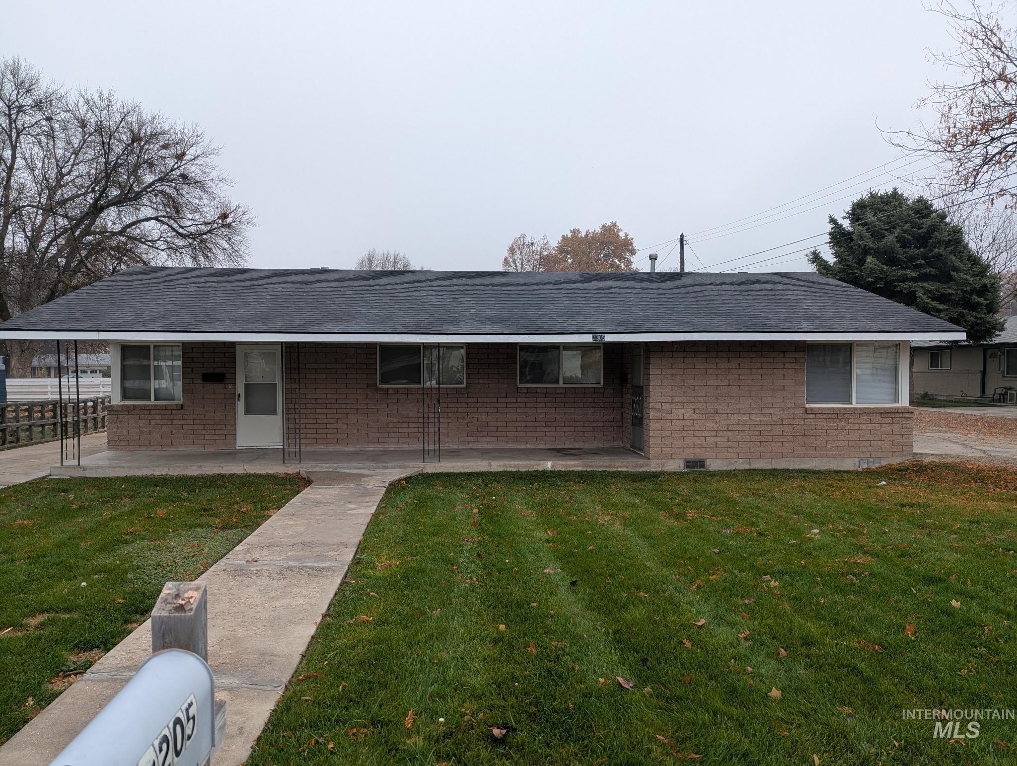 Ranch-style house featuring brick siding, a porch, a front lawn, and roof with shingles