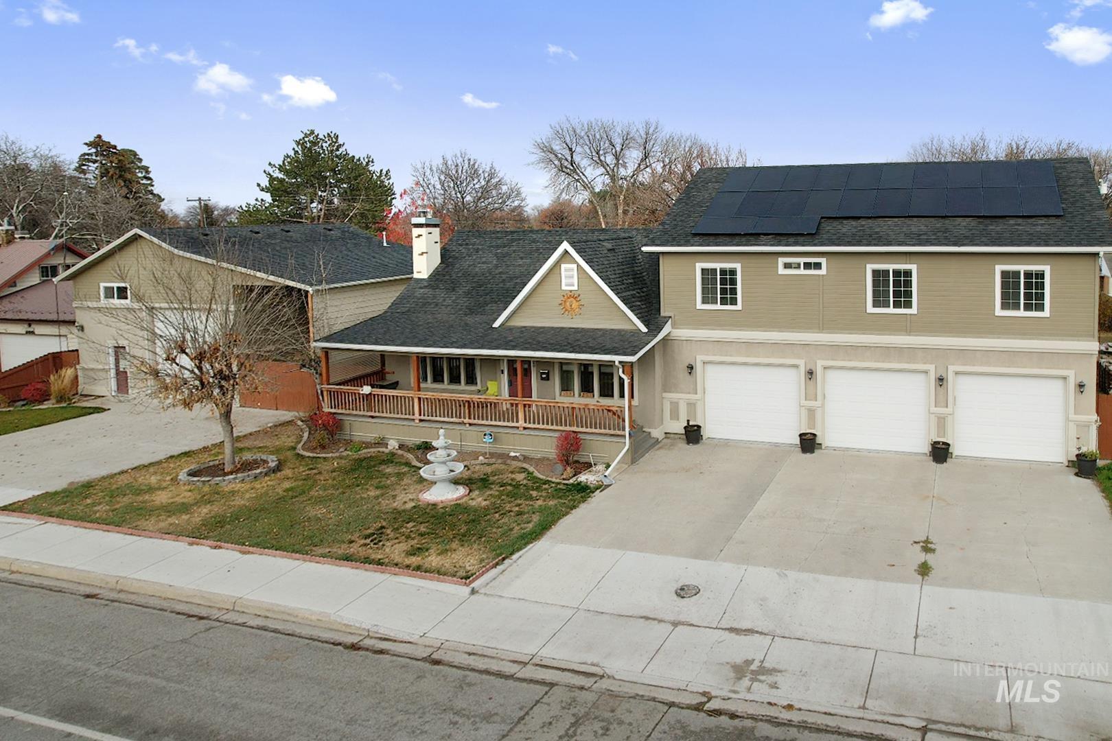 Traditional-style home featuring covered porch, concrete driveway, a shingled roof, roof mounted solar panels, and a garage