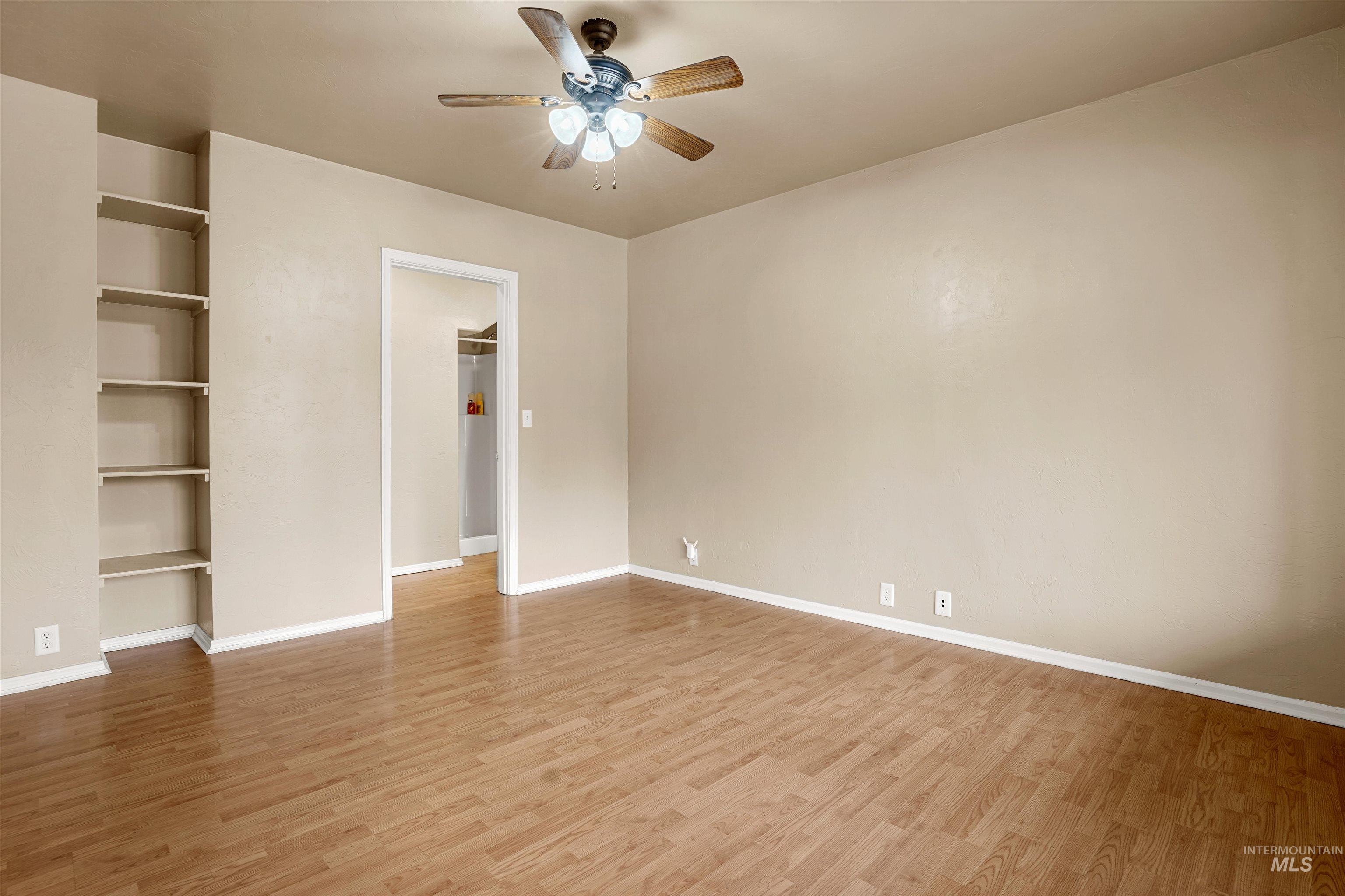 Unfurnished bedroom featuring light wood-style floors, a ceiling fan, and a walk in closet