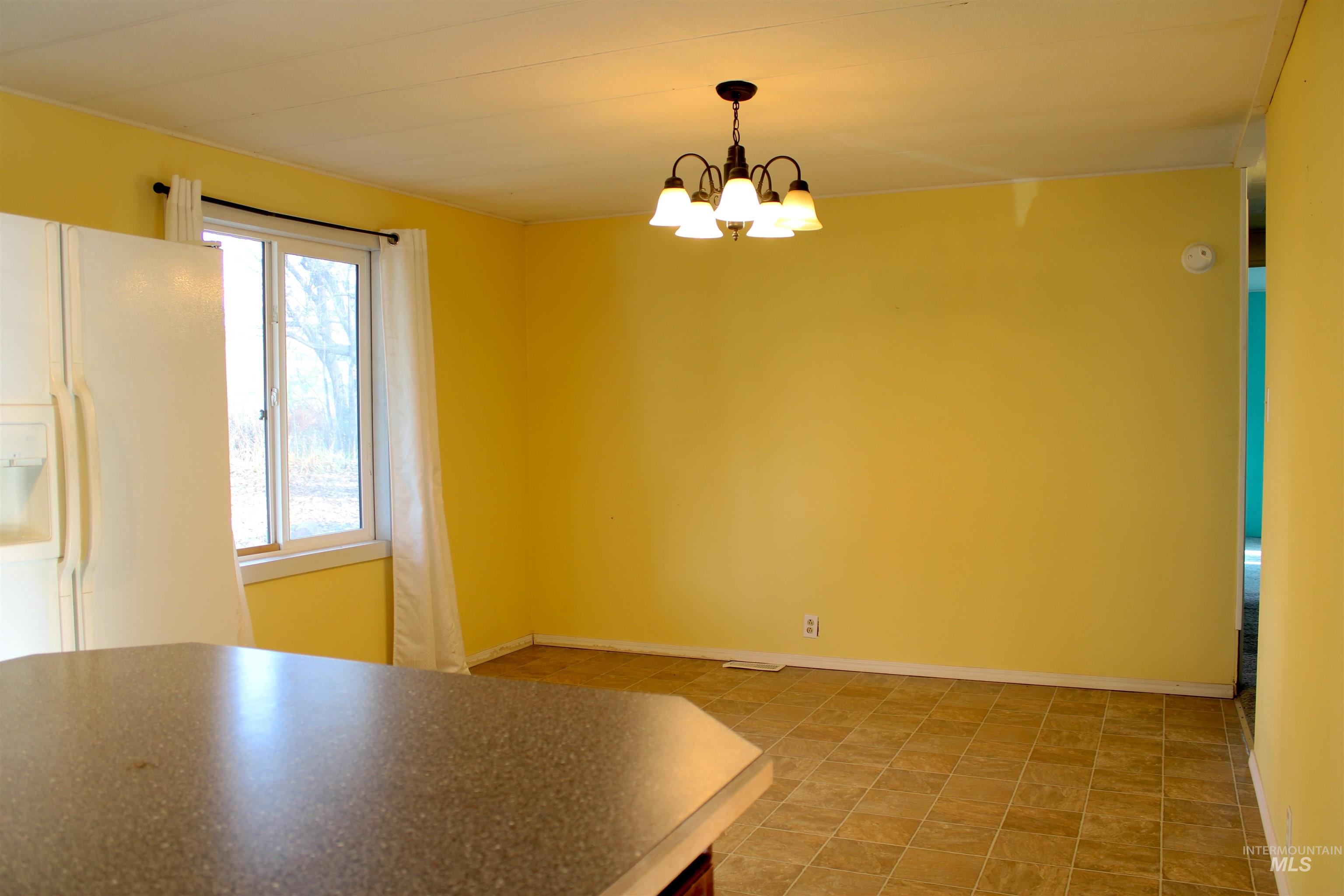 Unfurnished dining area featuring baseboards and a chandelier