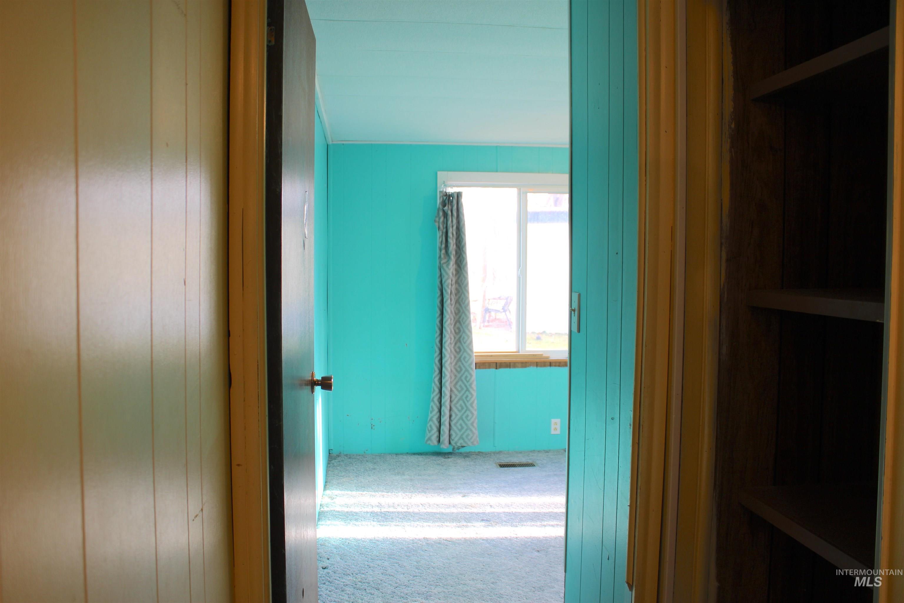 Hallway entry to bedroom 2 featuring carpet flooring and wooden walls