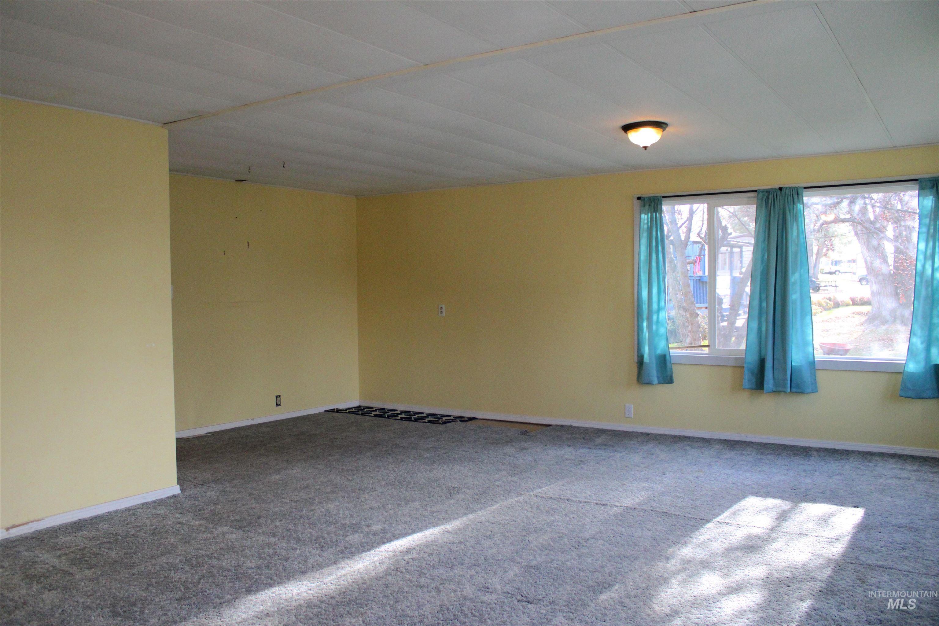 Carpeted spare room featuring baseboards
