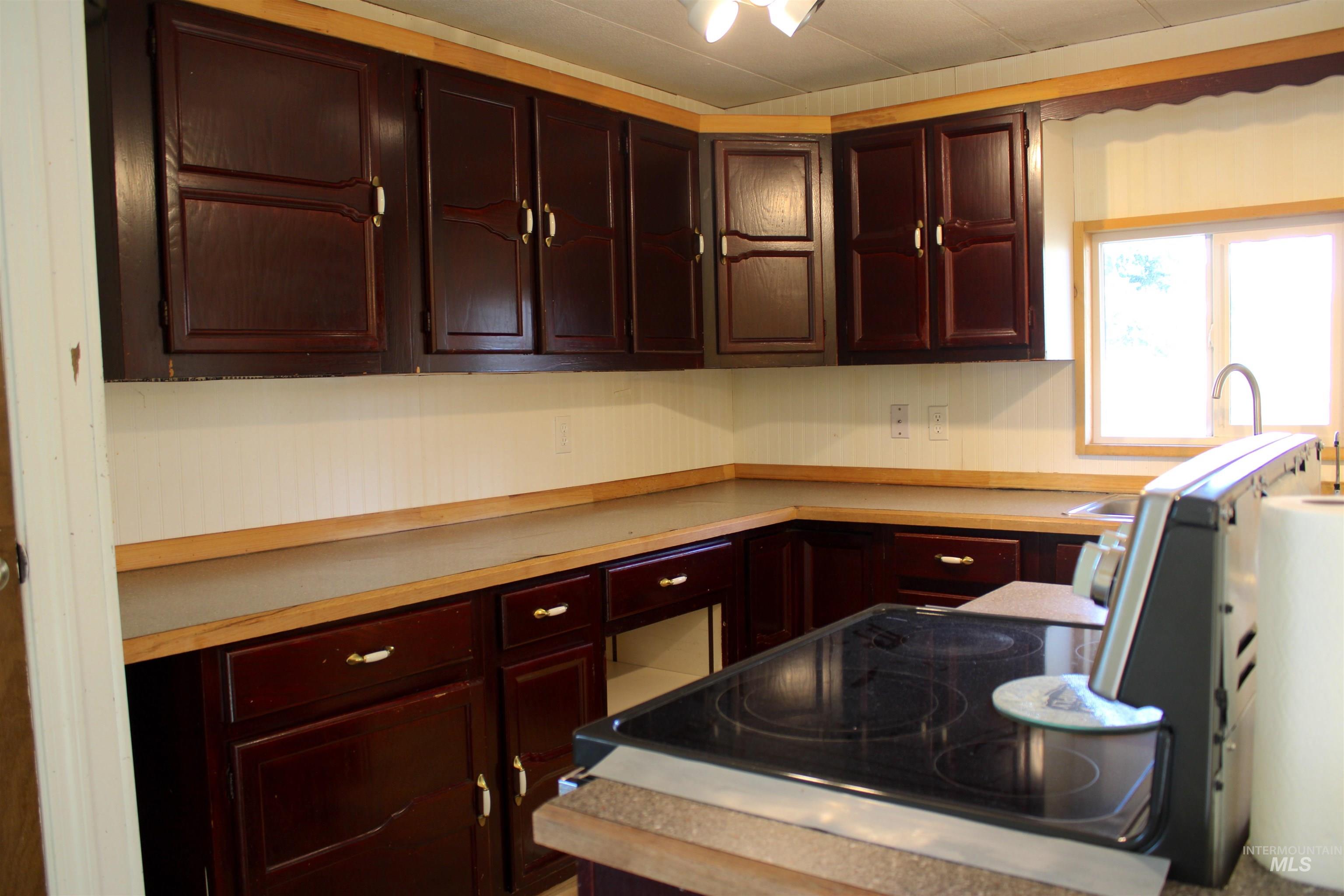 Kitchen featuring light countertops, black range with electric cooktop, and dark brown cabinetry