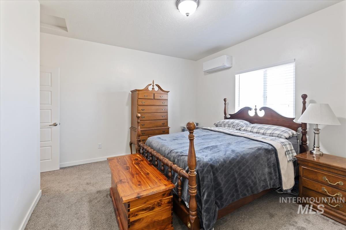 Bedroom featuring light colored carpet and a wall mounted AC