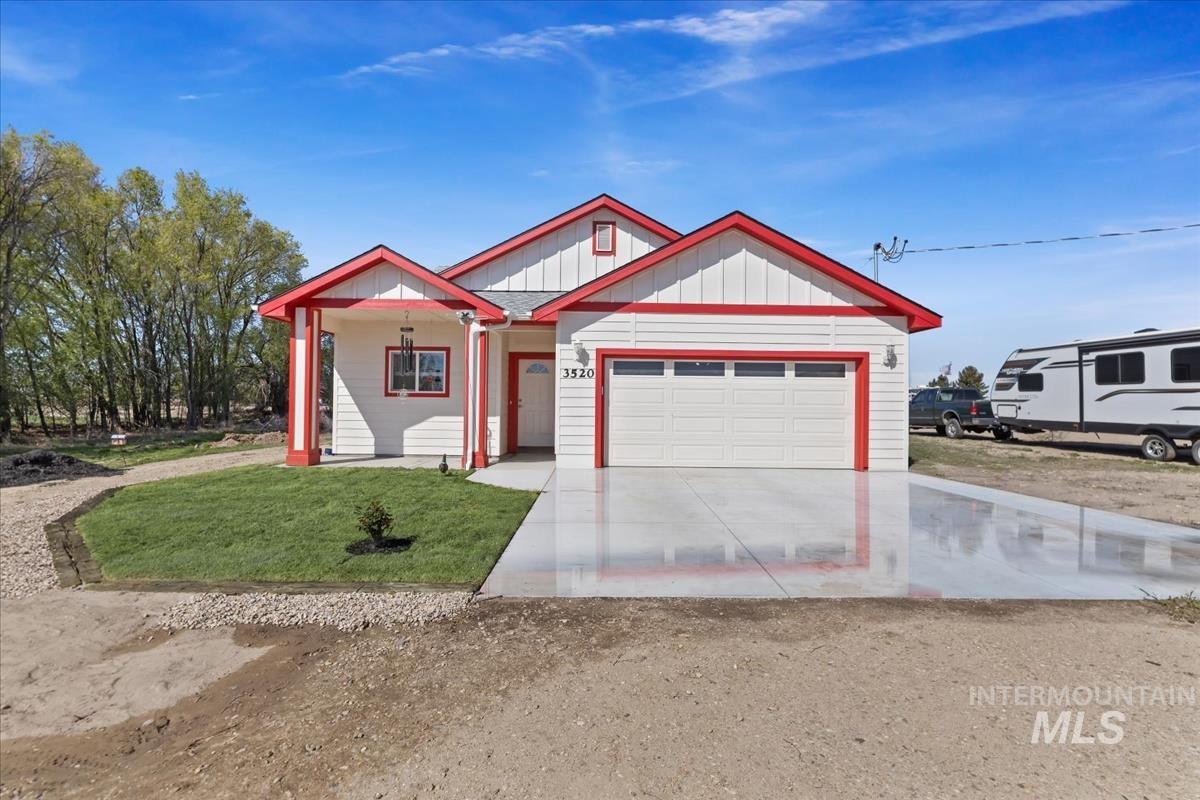 View of front of property with board and batten siding, driveway, covered porch, a front lawn, and a garage