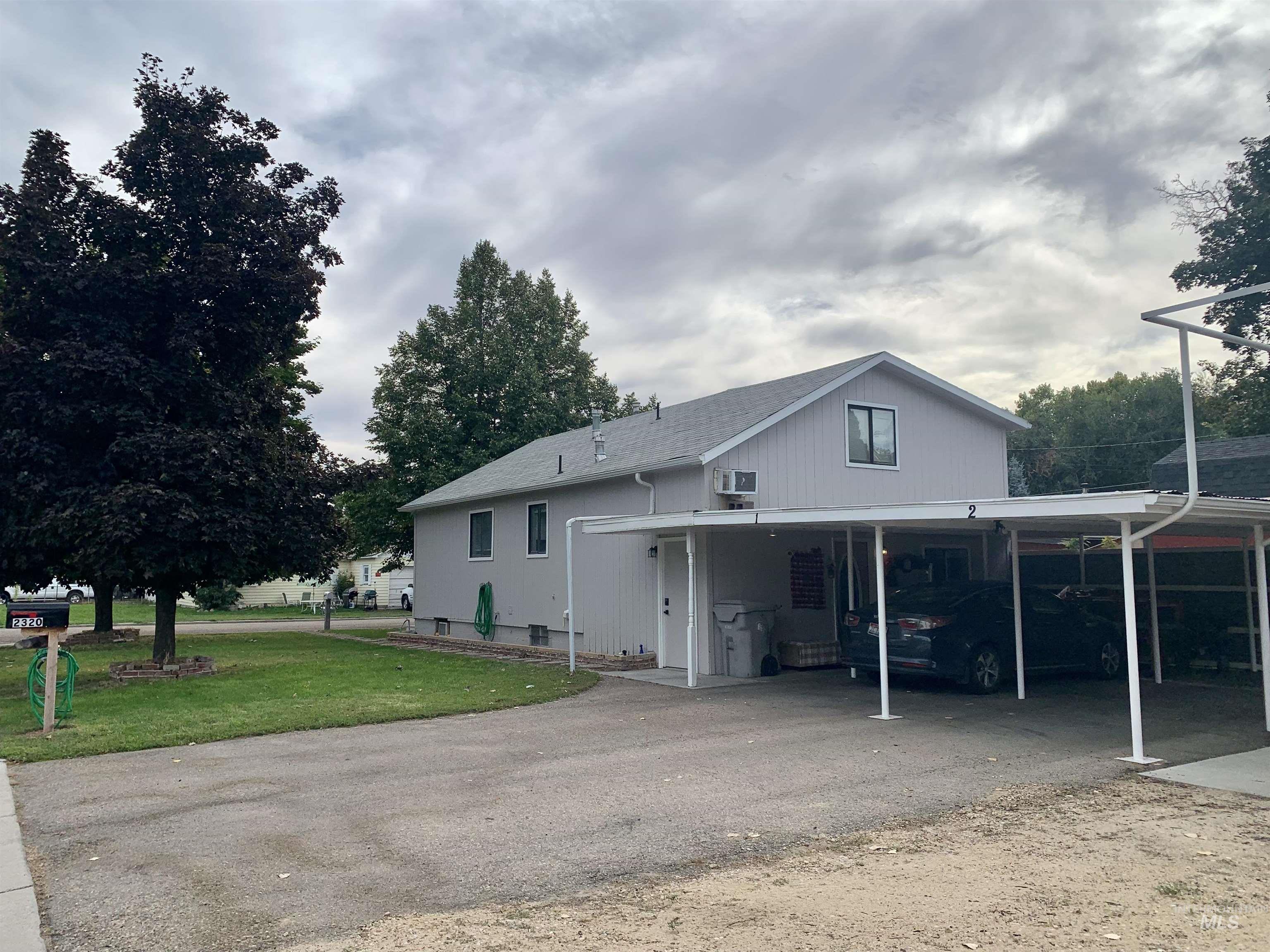 View from side of home with a carport, driveway, and a front yard