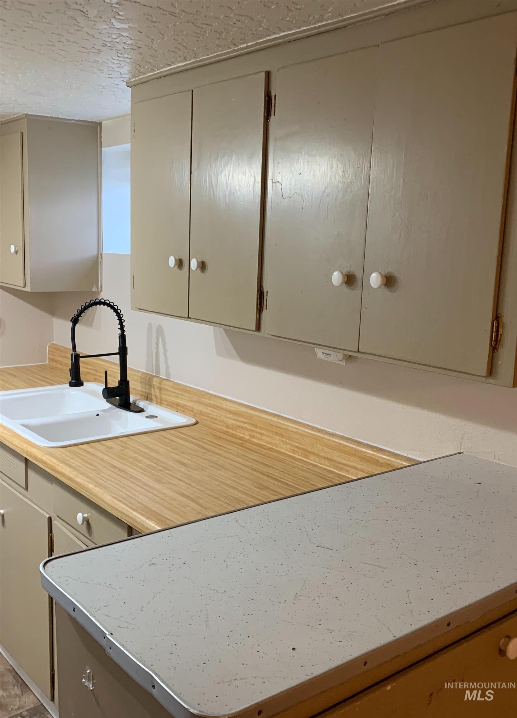 Kitchen featuring light countertops, a textured ceiling, and cream cabinetry