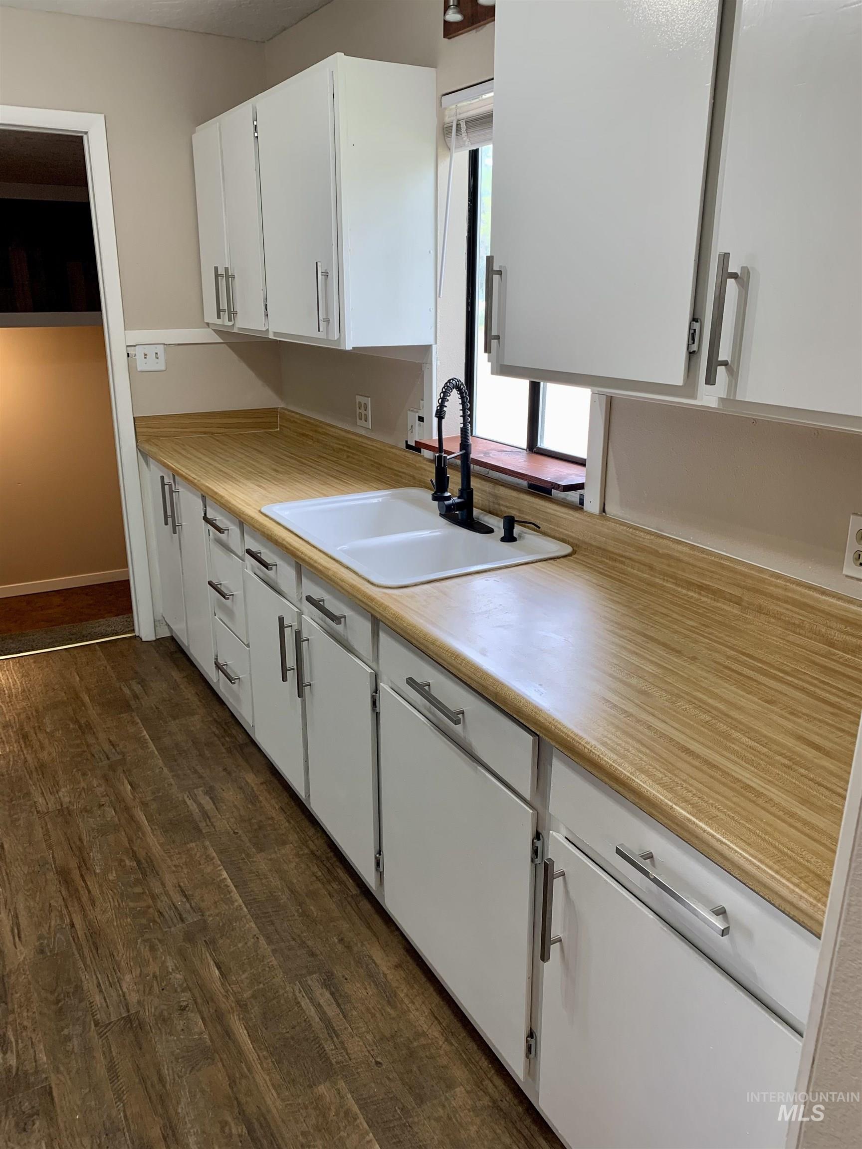 Kitchen featuring white cabinetry, dark wood-style floors, and light countertops