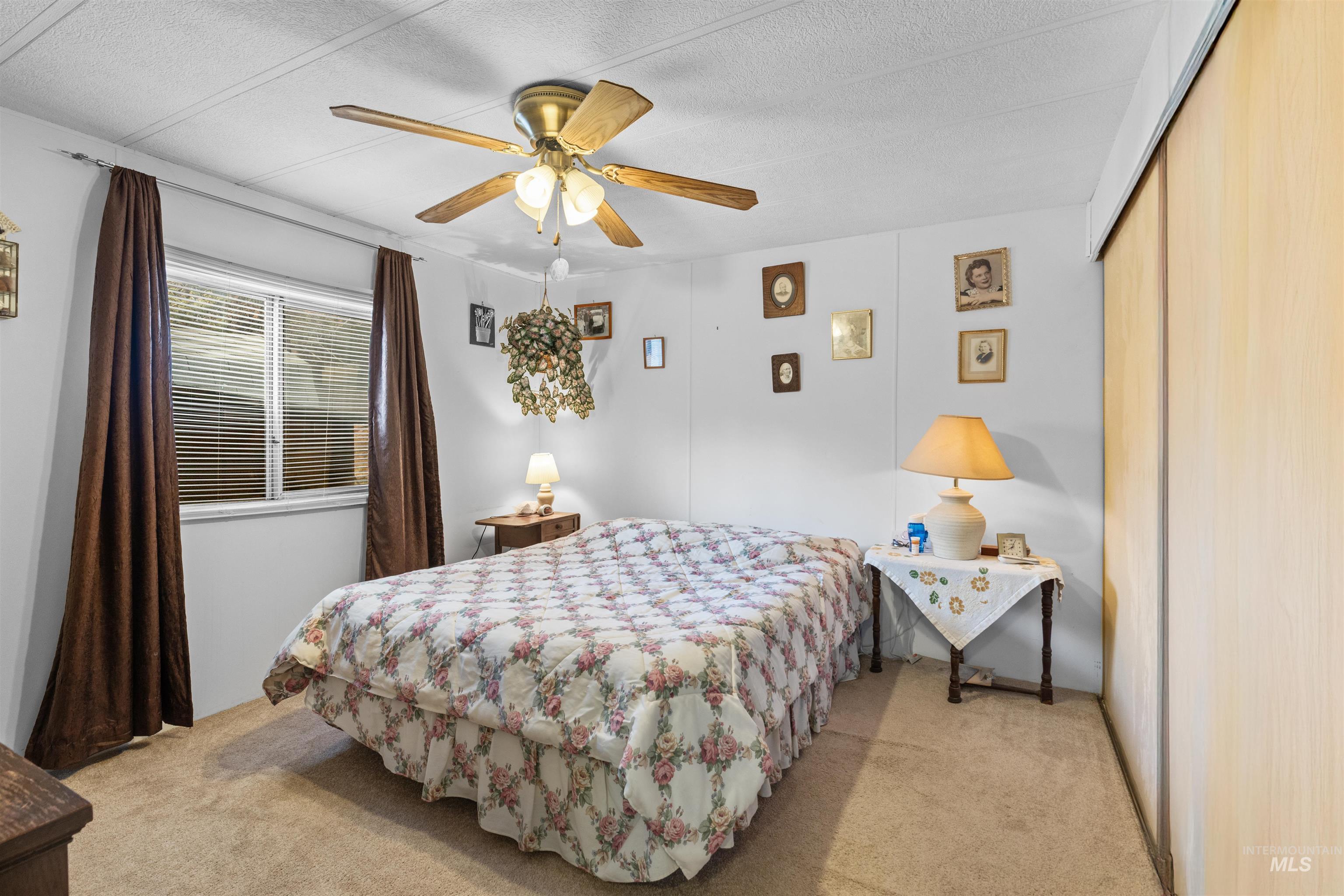 Bedroom with light colored carpet, ceiling fan, and a textured ceiling