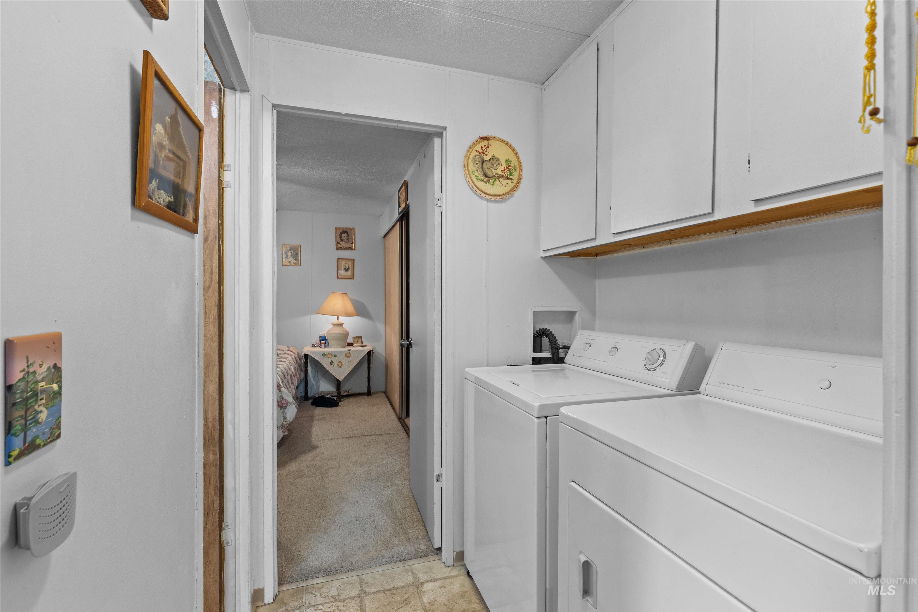 Laundry room with cabinet space, washing machine and clothes dryer, and light colored carpet
