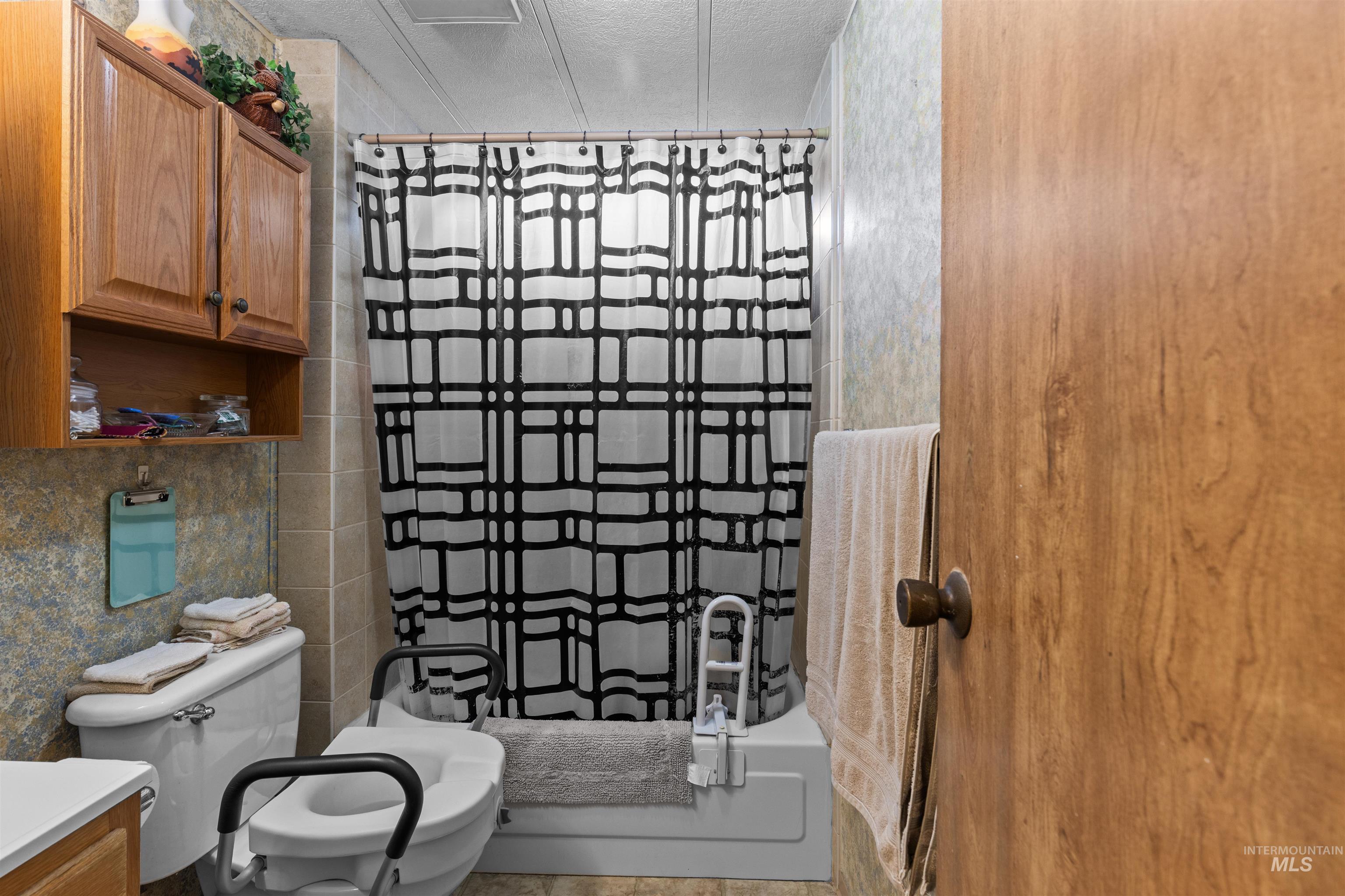 Bathroom with tile walls, vanity, a textured ceiling, and shower / tub combo
